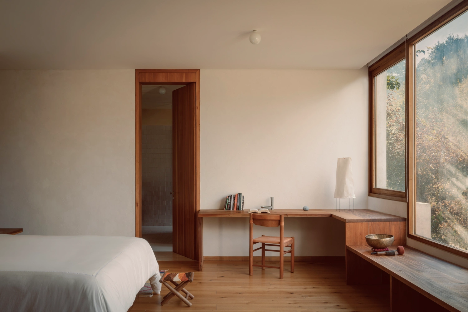 House Between Two Rivers by Taller 3000 — A bedroom interior articulated through timber furnishings and expansive glazing.