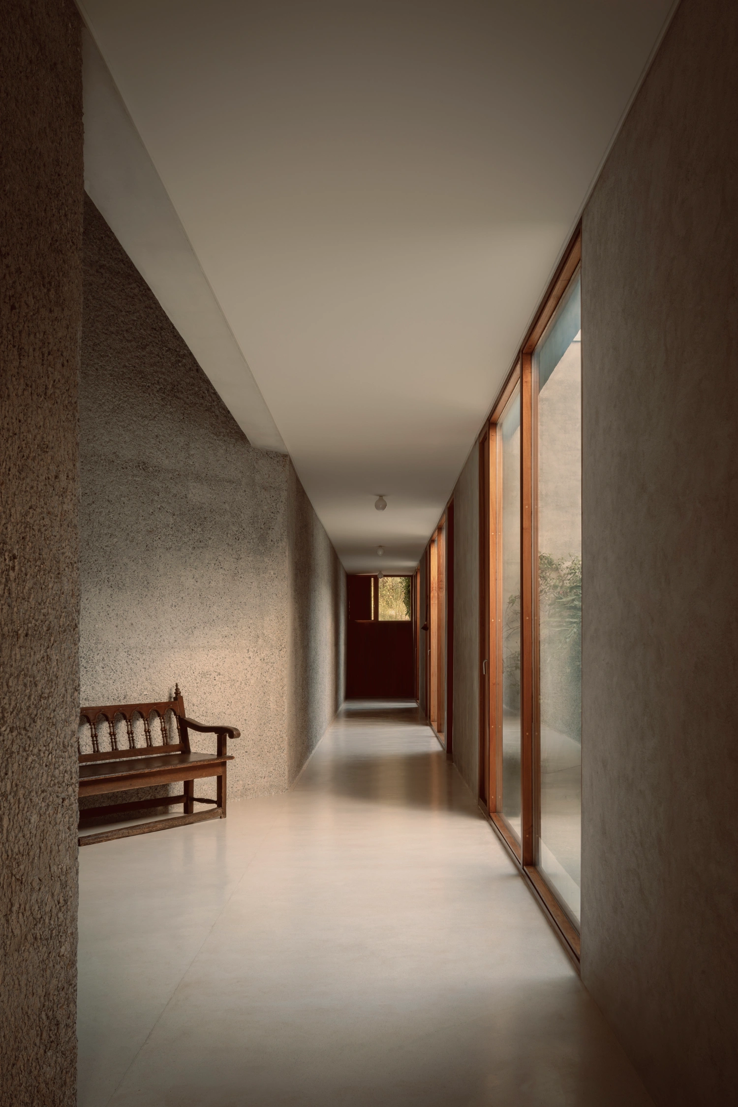 House Between Two Rivers by Taller 3000 — A rendered concrete corridor extends into depth, its textured walls bearing visible weathering patterns and water stains.