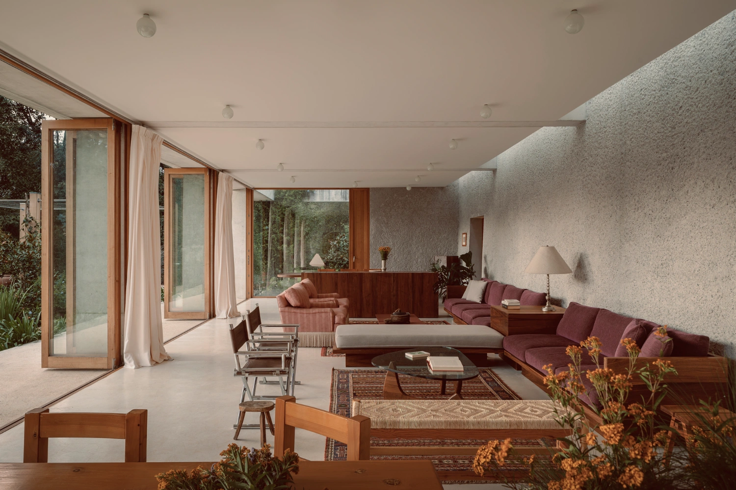 House Between Two Rivers by Taller 3000 — The living room unfolds as a horizontal expanse defined by wood and render.