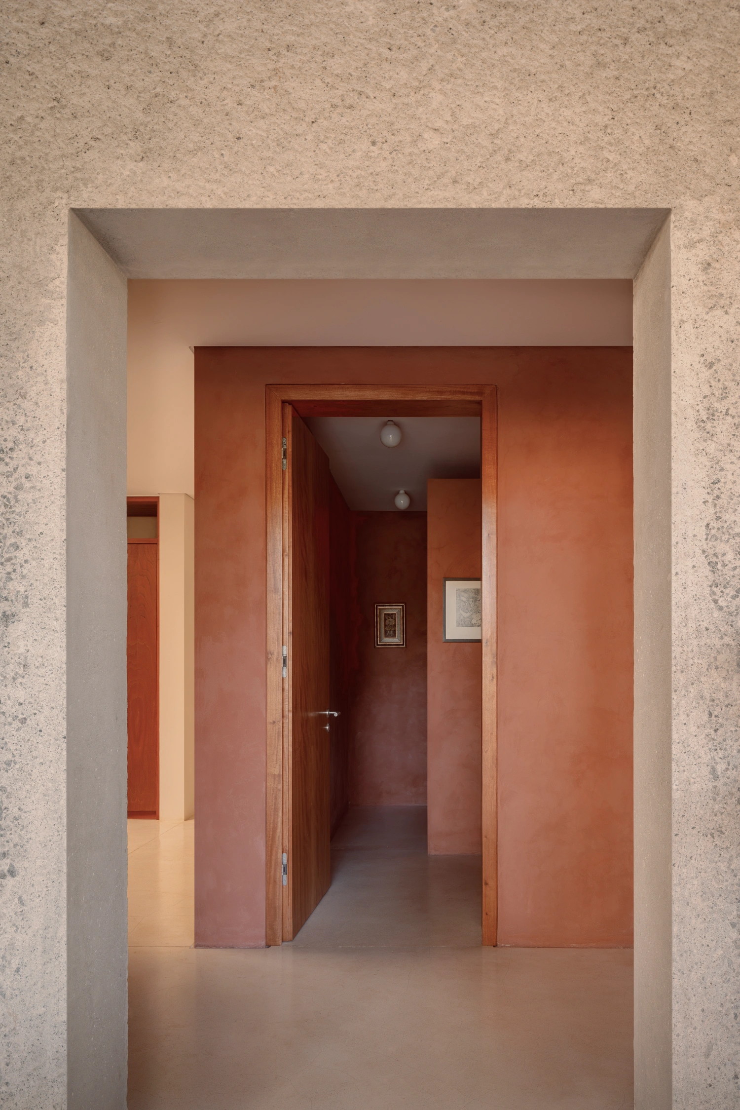 House Between Two Rivers by Taller 3000 — A layered passage through the house's interior reveals the sequential arrangement of rendered walls in terracotta and cream tones.