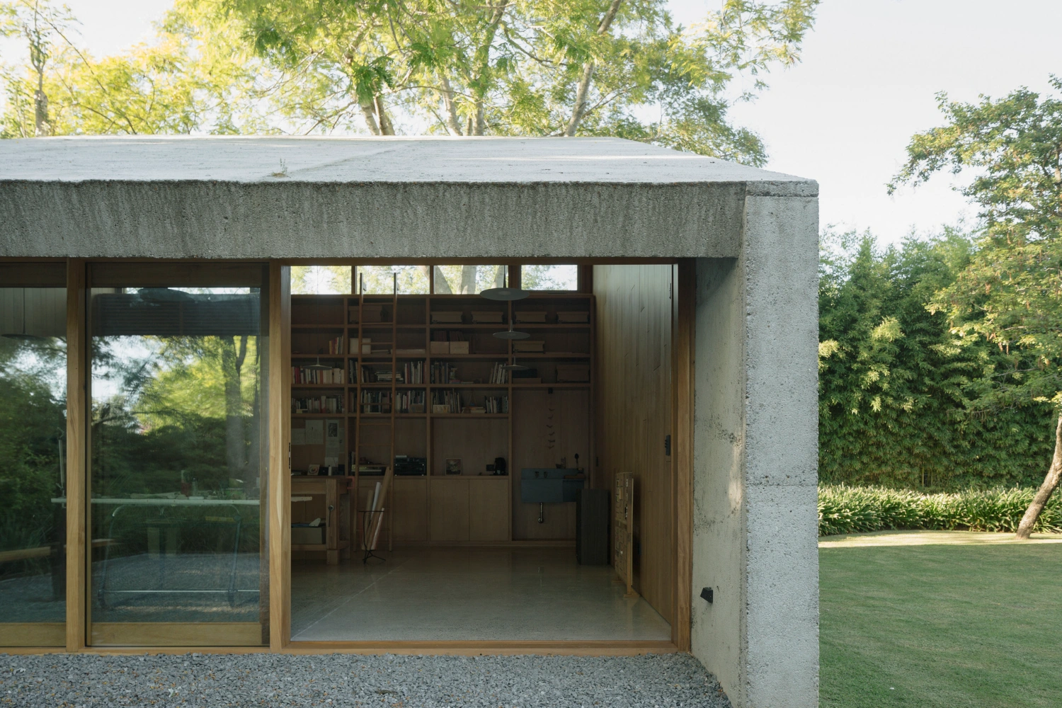 Atelier Workshop by Agustín Berzero — The workshop presents itself as a monolithic concrete structure set within a dense tree canopy, its raw material surface visibly weathered and textured.
