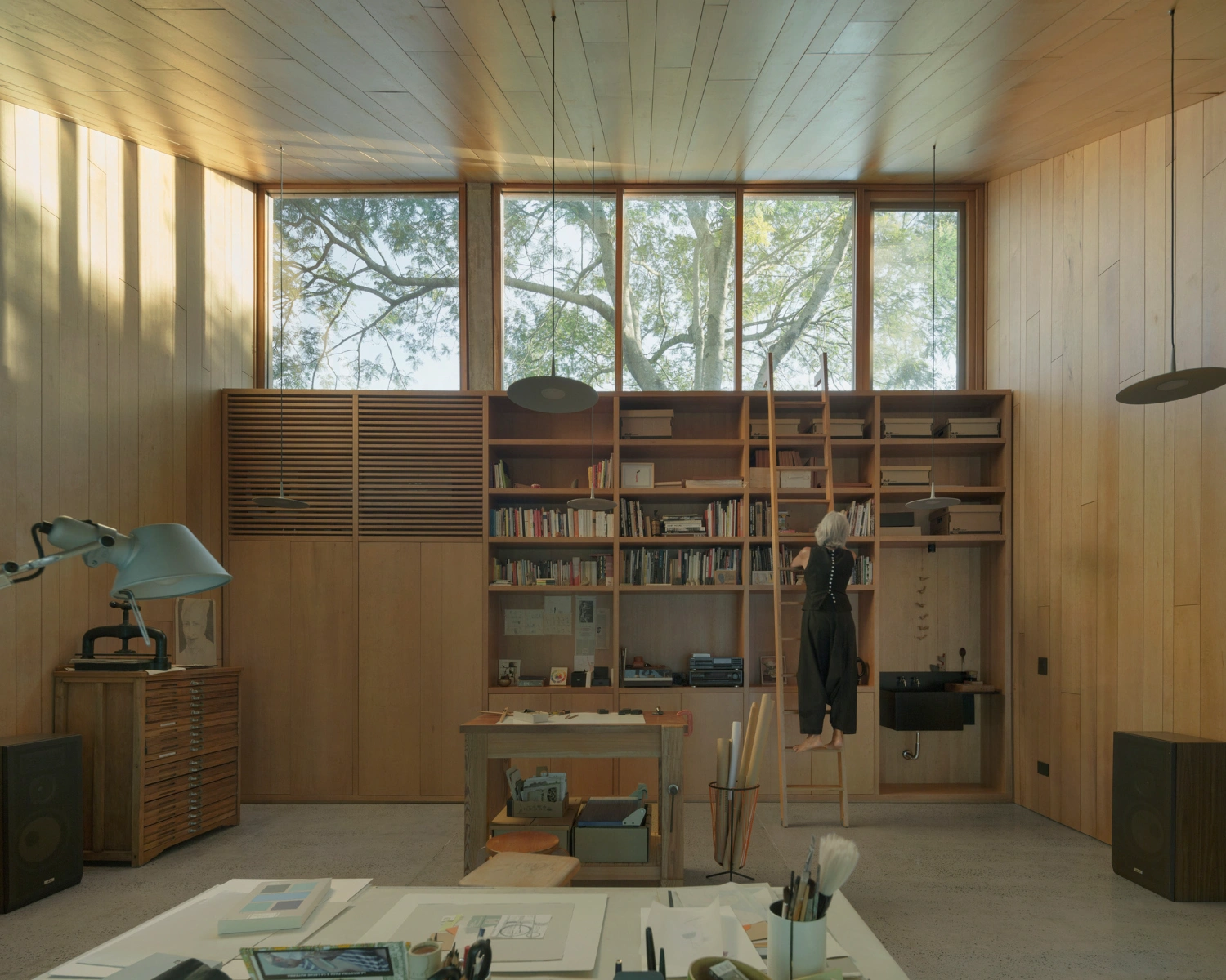 Atelier Workshop by Agustín Berzero — Interior view of the atelier revealing a timber-lined workspace defined by a floor-to-ceiling shelving system in light wood.