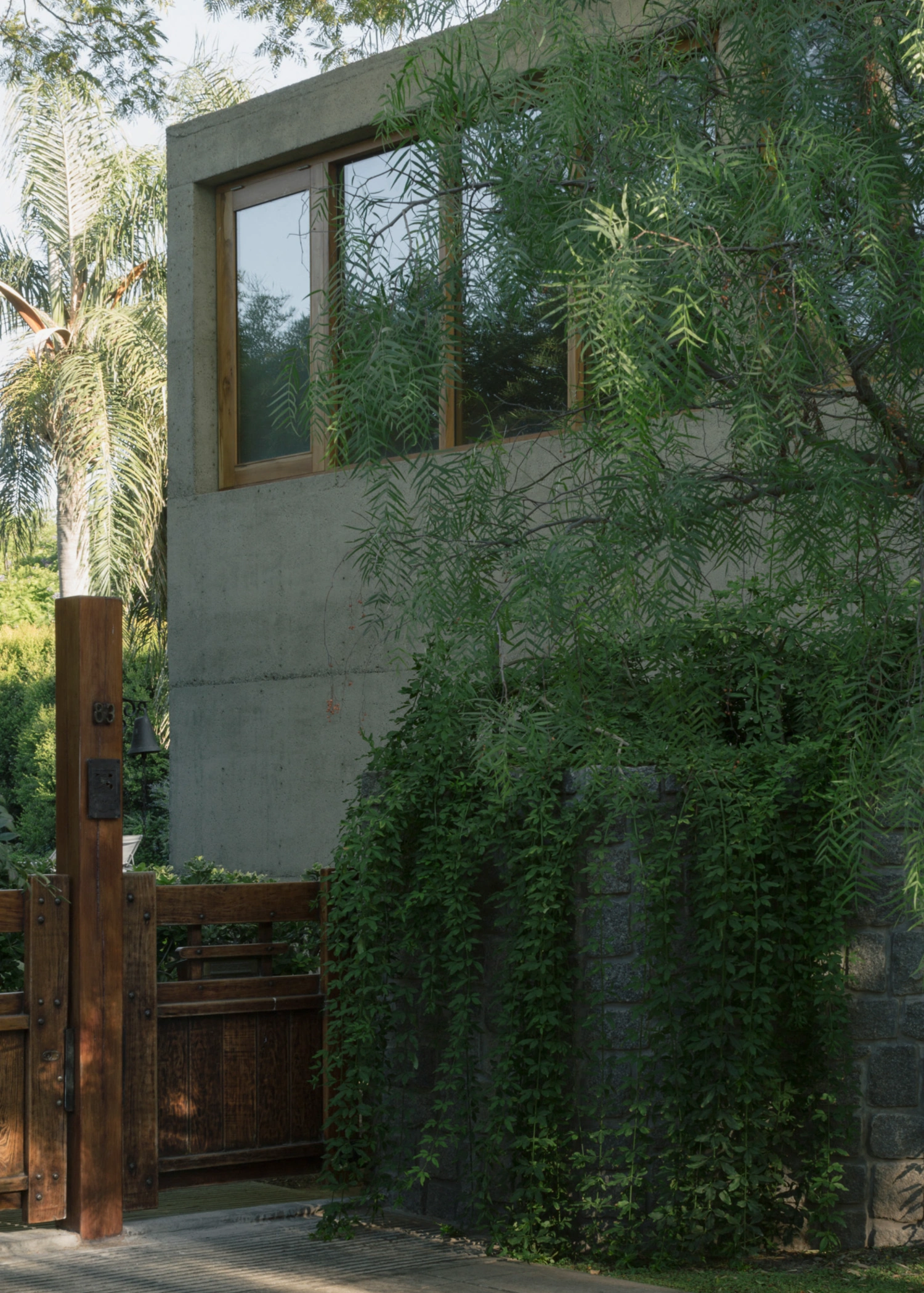 Atelier Workshop by Agustín Berzero — A monolithic concrete volume rises from gravel courtyard, its southern face punctured by a timber-framed glazing strip that frames interior light against...
