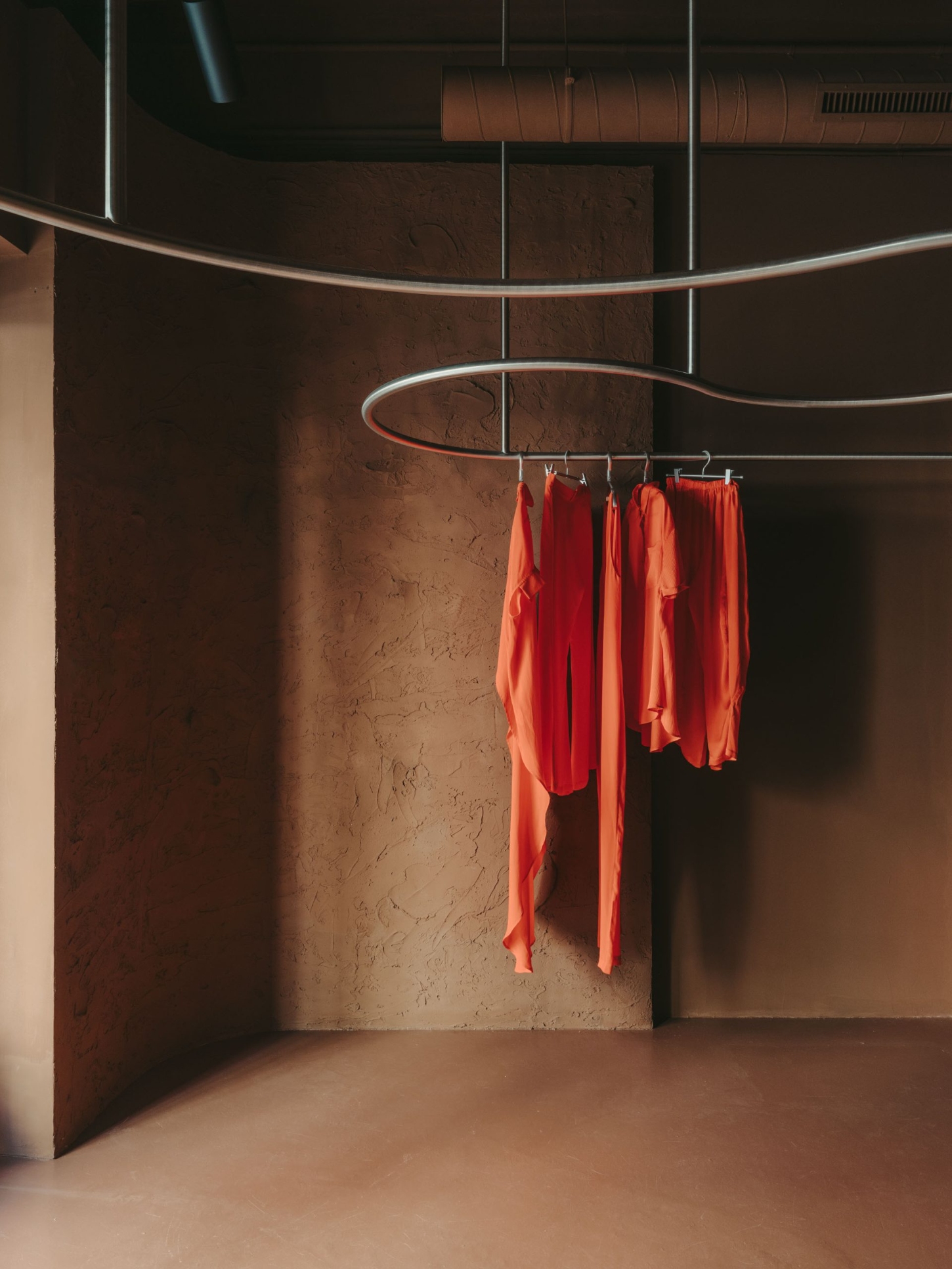 GN0 store by Cristina Cirera — A clothing display suspended on serpentine stainless steel rails that curve through the interior volume.