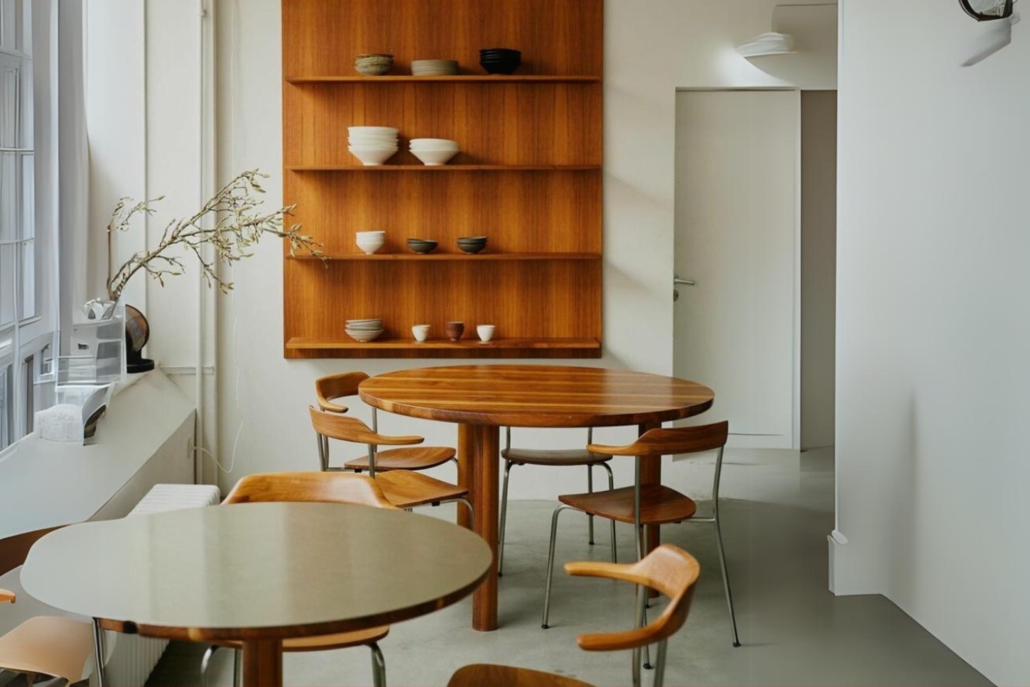 Julius in Berlin — Two round walnut tables with bentwood chairs occupy the foreground of Julius's dining space in Wedding, Berlin.