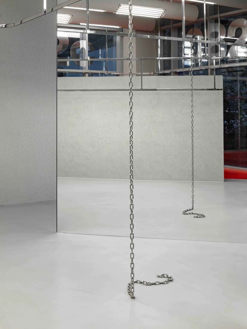 032c Gallery in Seoul by Gonzales Haase AAS — Two metal chains suspended vertically from the ceiling plane hang above the white floor of the 032c Gallery Seoul interior.