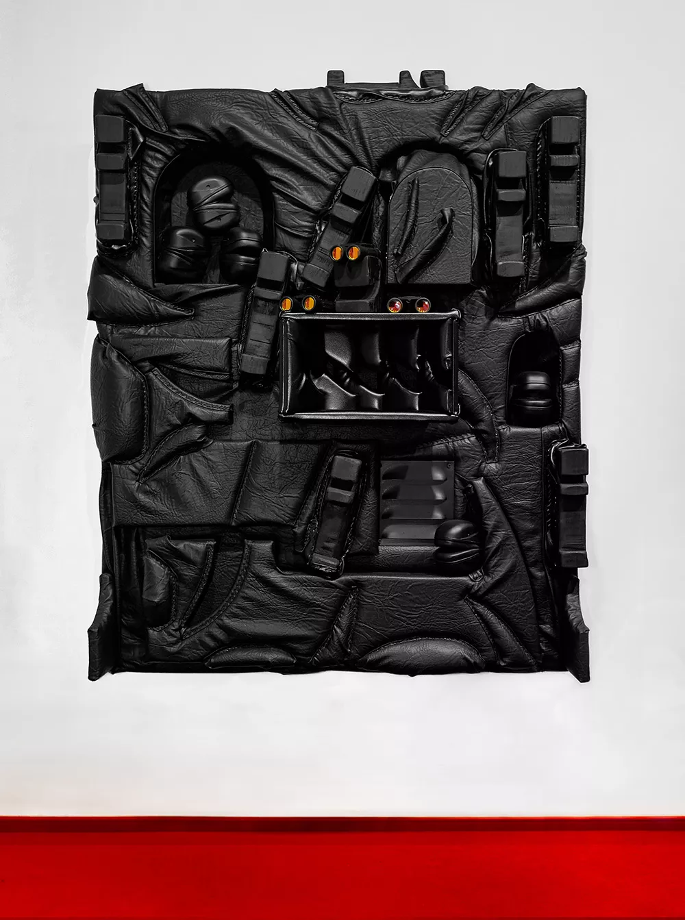 Productive Narcissism at 032c Gallery in Berlin — Overhead view of a modular leather backpack system arranged against a white background, its black hide surface creased and worn from use.