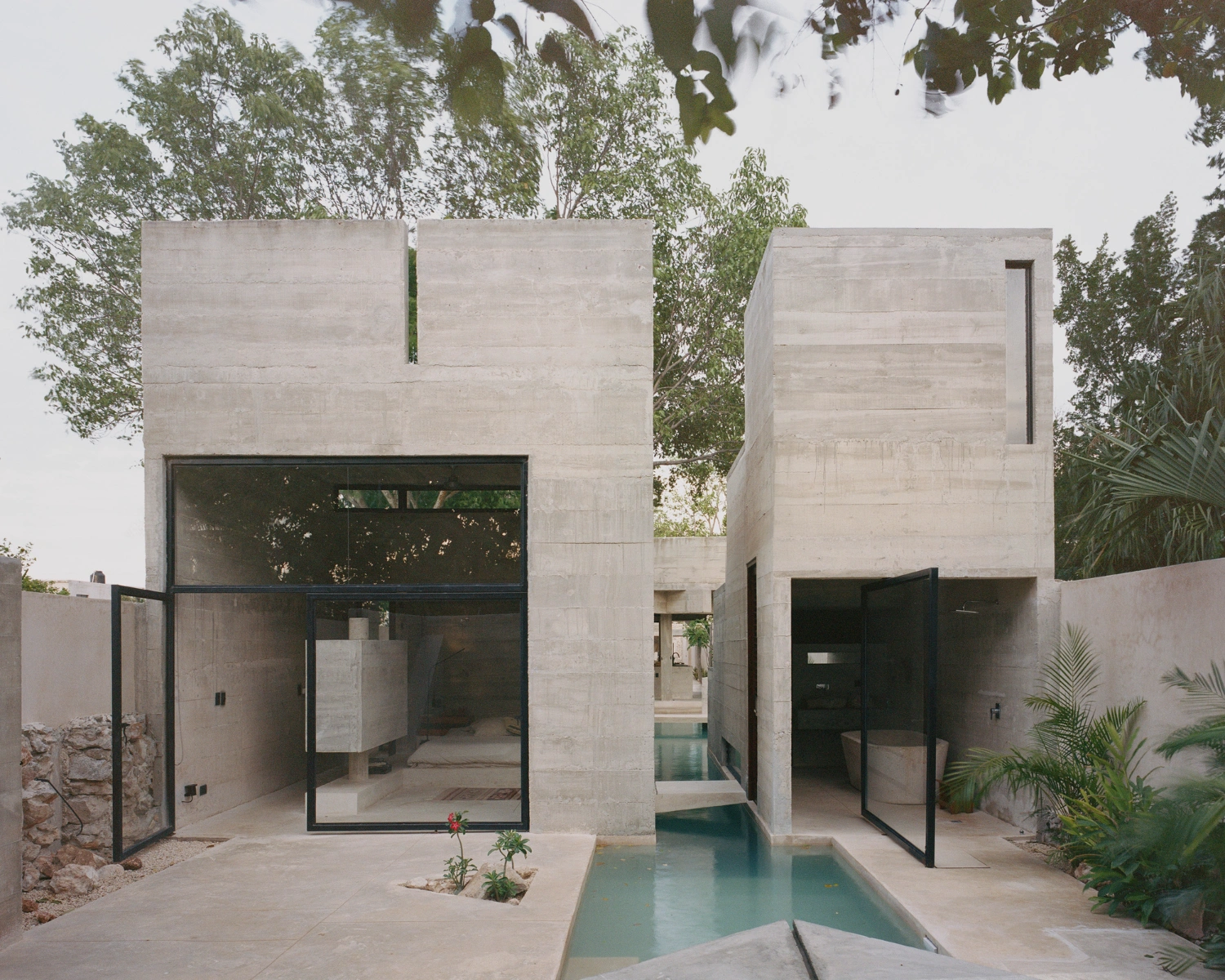 House in Los Cocos by Ludwig Godefroy Architecture — A narrow courtyard in Mérida frames two concrete pavilions connected by a rectangular water basin.