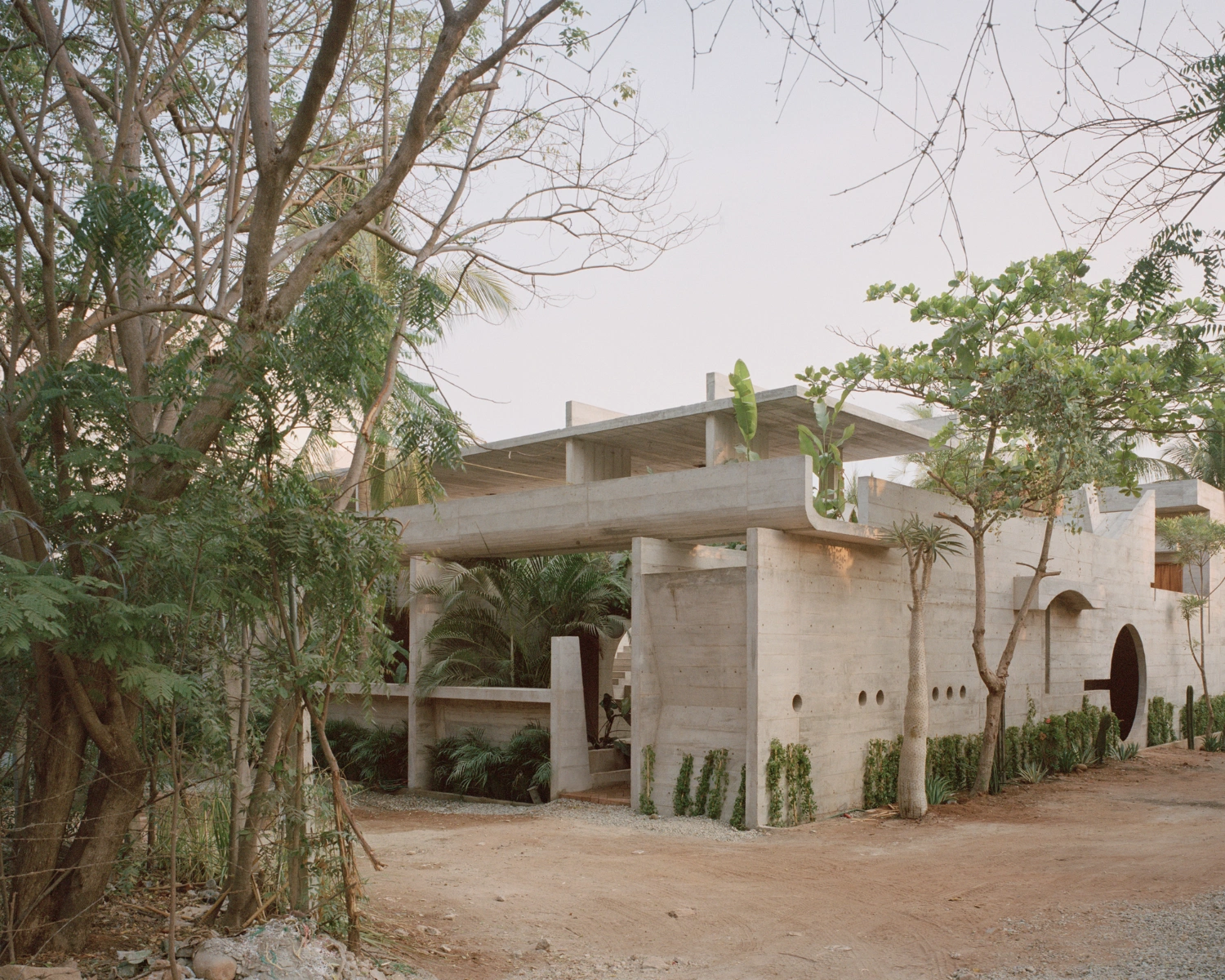 House TO by Ludwig Godefroy Architecture — House TO presents itself as a monolithic concrete structure nestled within mature tropical vegetation.