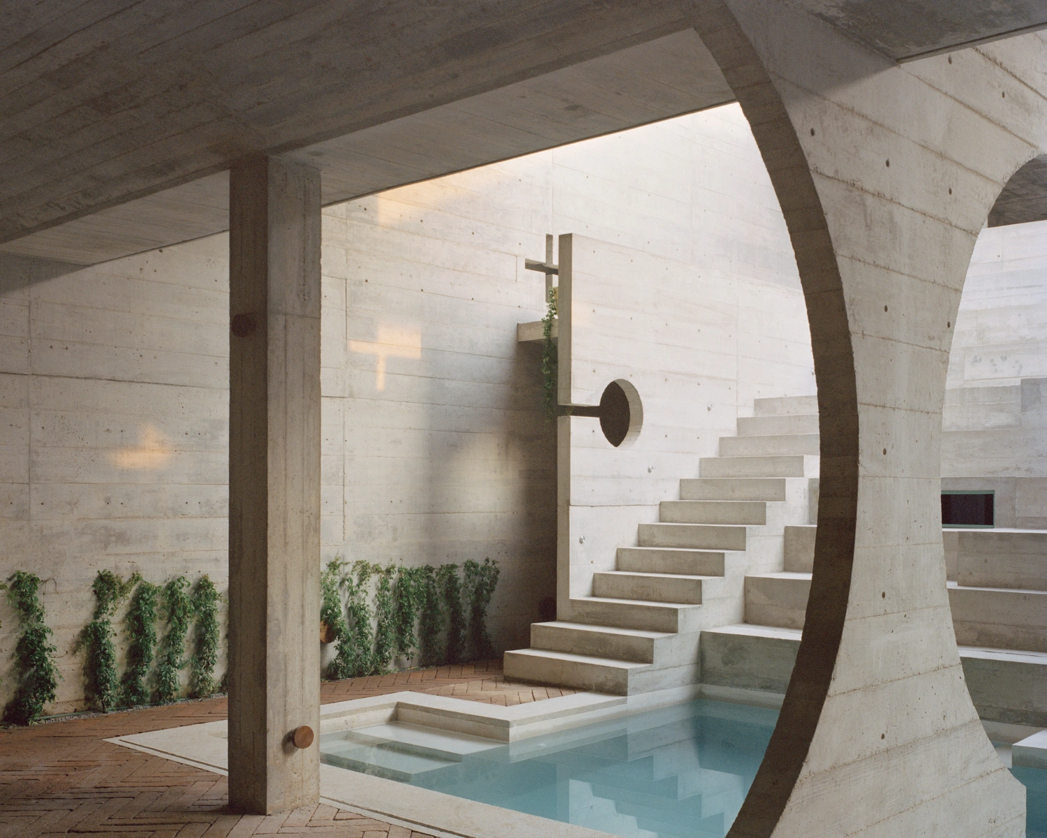 House TO by Ludwig Godefroy Architecture — A monolithic concrete structure frames an interior courtyard where water meets architecture.
