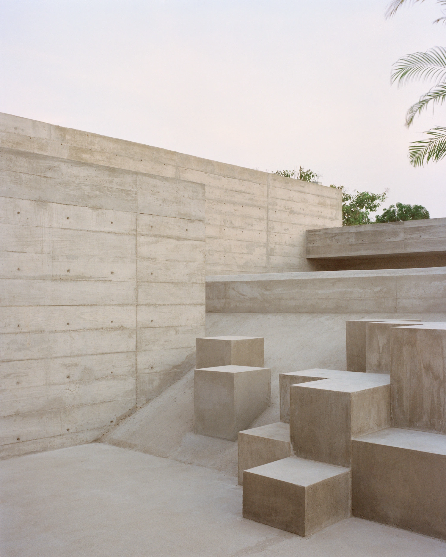 House TO by Ludwig Godefroy Architecture — A monolithic concrete courtyard revealed in cross-section, where board-formed walls demonstrate visible pour lines and formwork marks.