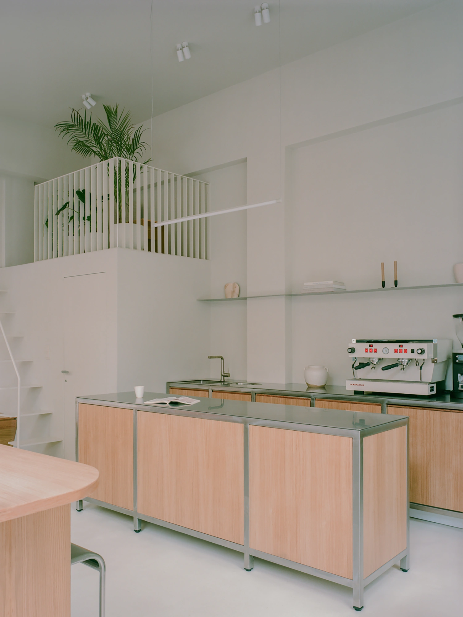 Moden Café by Georgios Apostolopoulos — The ground-floor café interior features a custom oak counter with integrated metal framing and bar seating, positioned as the dominant spatial element.