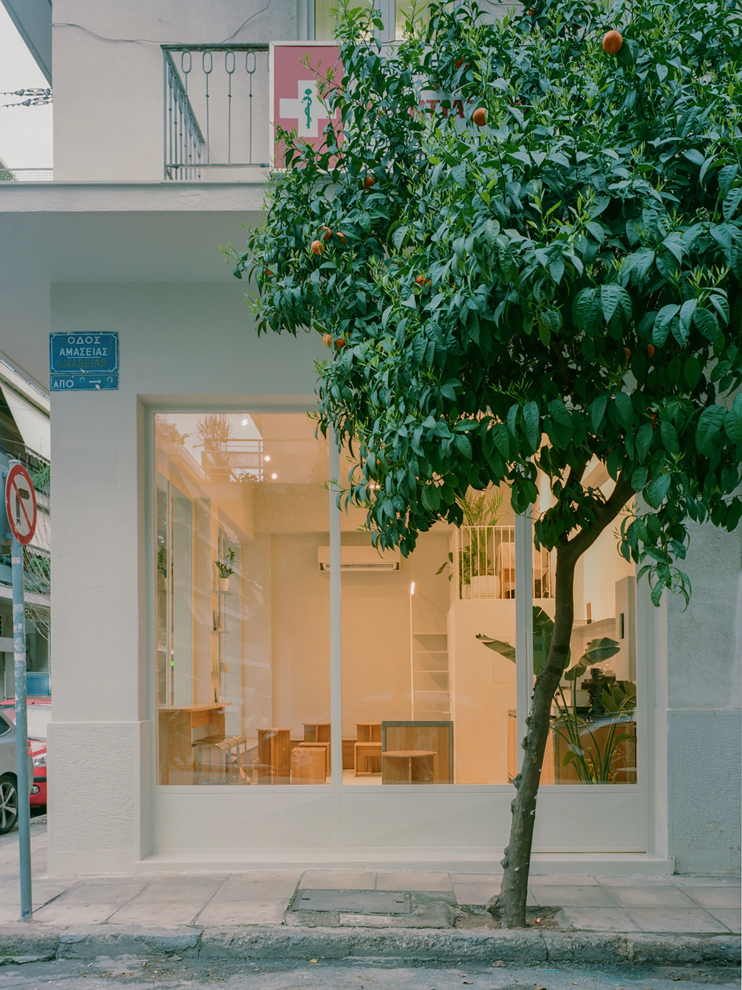 Moden Café by Georgios Apostolopoulos — Street-facing storefront of Moden Café captured at dusk, showing the full-height glazed facade with white aluminum framing.
