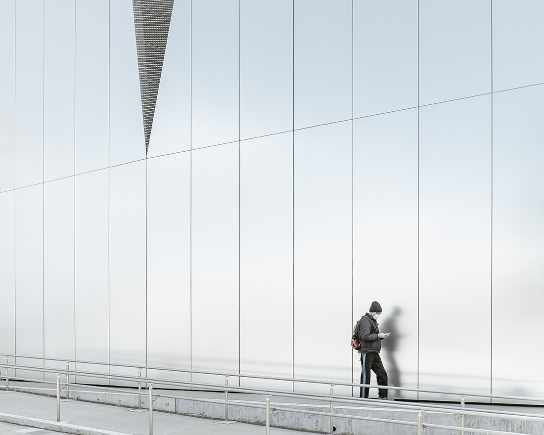 Sumida Hokusai Museum by Kazuyo Sejima — A solitary figure in dark winter clothing stands against the Sumida Hokusai Museum's monumental aluminum facade, dwarfed by the vertical grid of paneled...