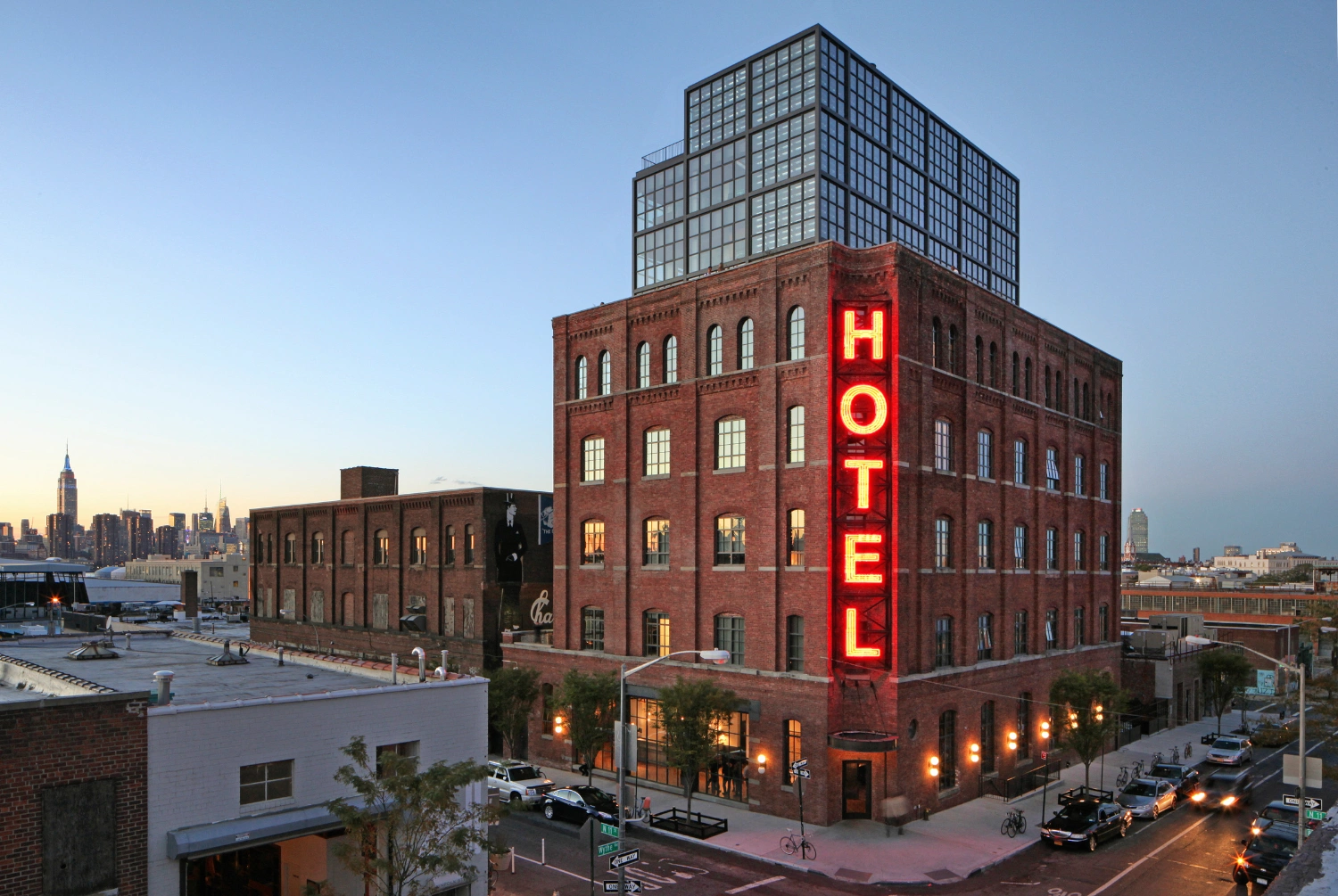 Wythe Hotel New York by Morris Adjmi Architects — The Wythe Hotel presents a deliberate material collision: a preserved cast-iron-era brick facade with regular fenestration anchors the lower stories, while...