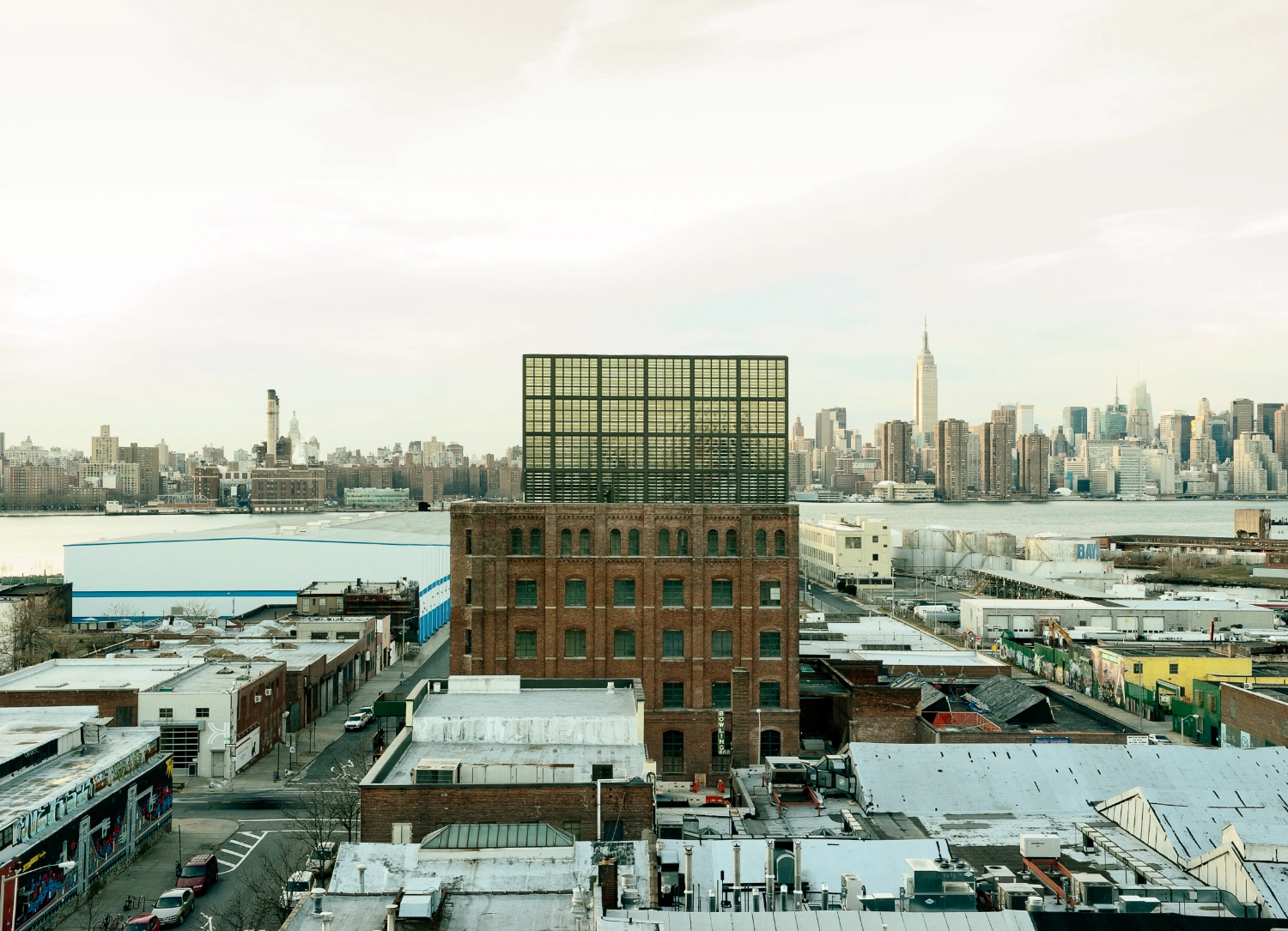 Wythe Hotel New York by Morris Adjmi Architects — Aerial perspective reveals the Wythe Hotel's defining material collision: a geometric green-gridded glass and steel penthouse sits atop a weathered brick...