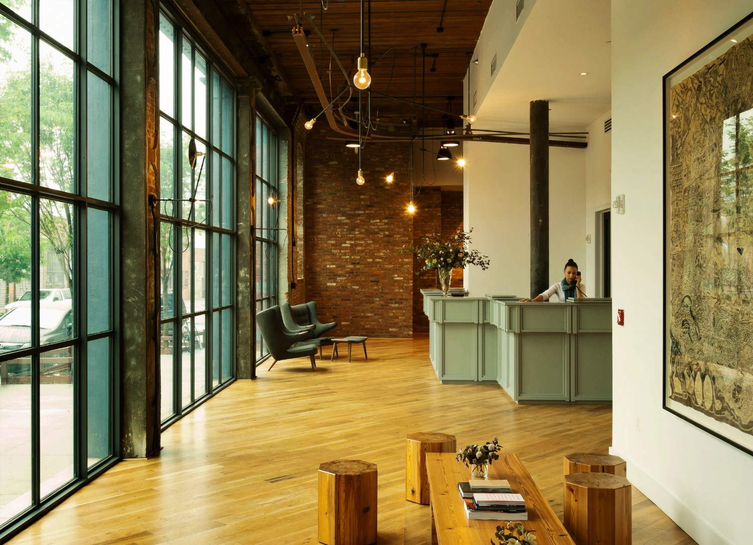 Wythe Hotel New York by Morris Adjmi Architects — The hotel lobby demonstrates a deliberate material archaeology, where preserved brick masonry and cast-iron structural columns coexist with contemporary...