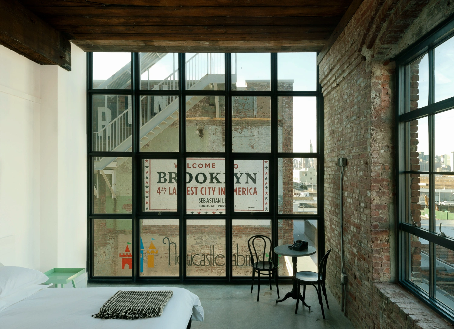 Wythe Hotel New York by Morris Adjmi Architects — A corner bedroom within the converted cooperage showcases the hotel's material dialogue through its fenestration strategy.