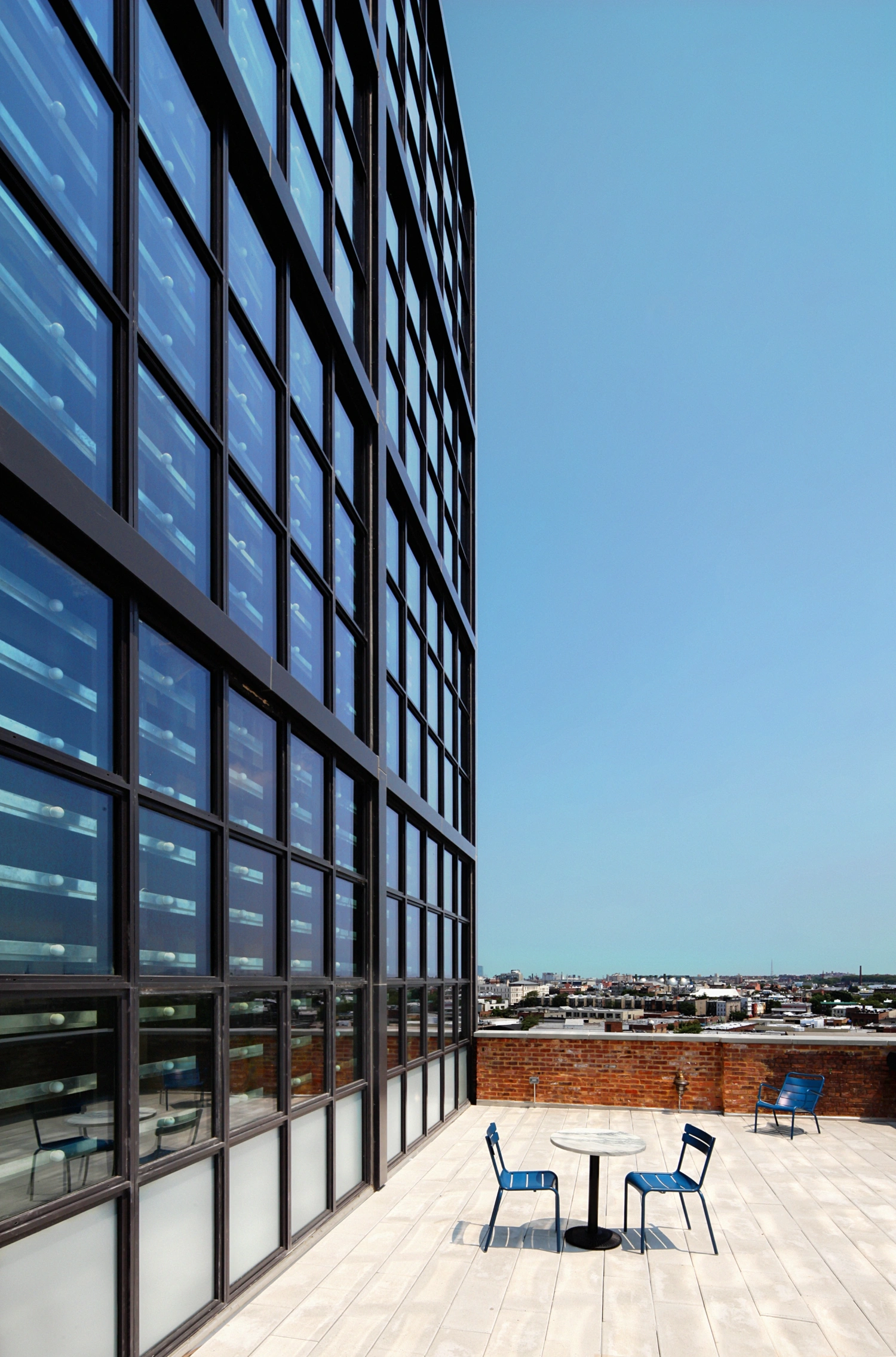 Wythe Hotel New York by Morris Adjmi Architects — The rooftop terrace of Wythe Hotel's glass-and-steel penthouse addition frames a studied composition of industrial persistence and contemporary intervention.