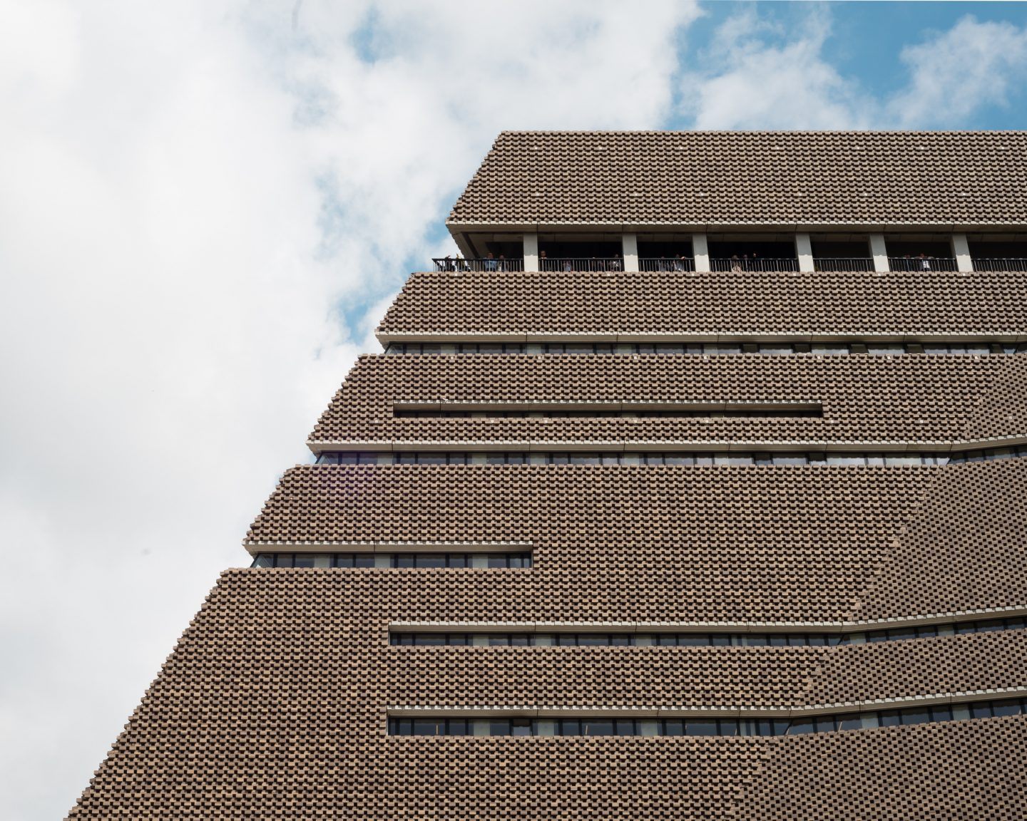 The Tate Modern by Herzog & de Meuron — A low-angle photograph captures the stepped brick facade of Tate Modern's converted power station, emphasizing the diagonal weave pattern of the terracotta...