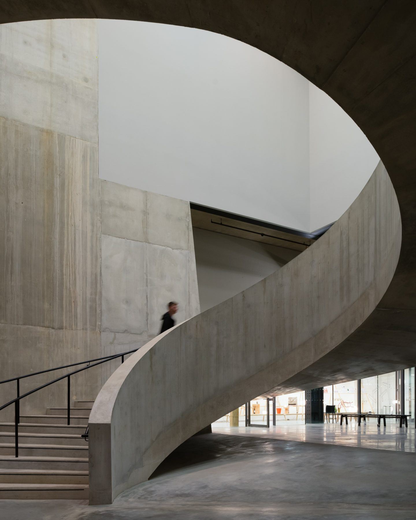 The Tate Modern by Herzog & de Meuron — A monolithic concrete spiral ramp ascends through the interior of the Bankside Power Station conversion, its smooth curved walls rising toward a bright...