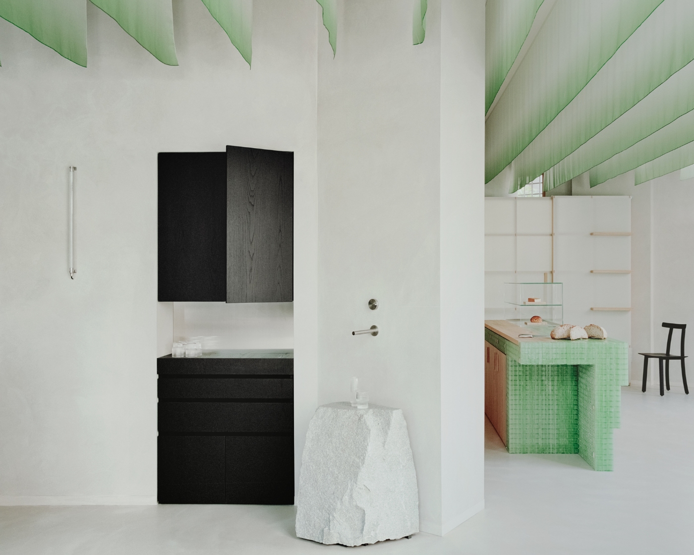 PAN Milano by studio wok — A bathroom vanity composition in PAN Milano combines a black-stained timber cabinet with integrated mirror against white plaster walls.