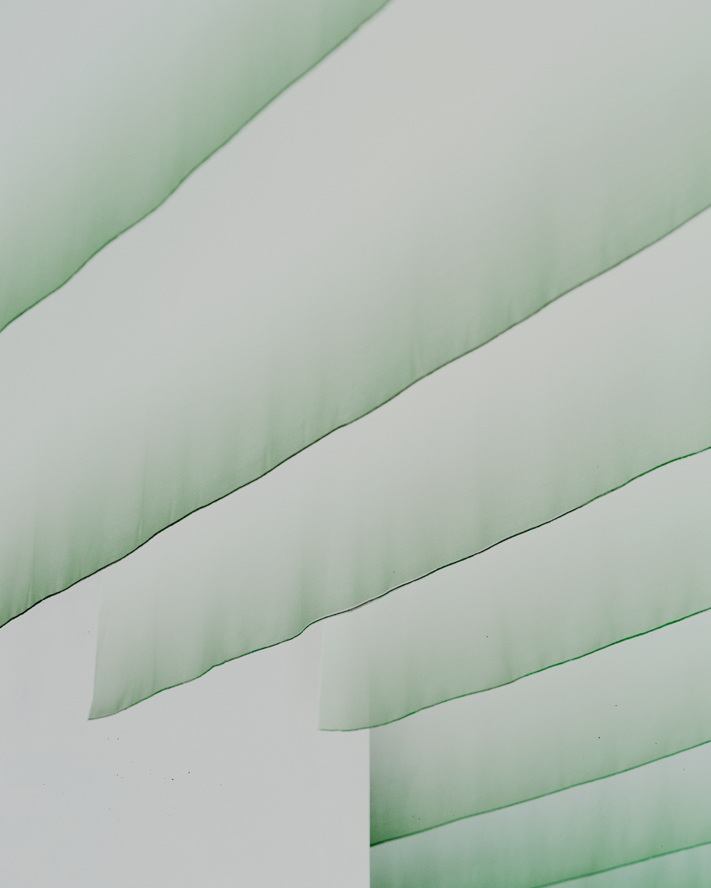 PAN Milano by studio wok — Overhead view of suspended translucent green fabric panels creating a rhythmic linear composition across the ceiling plane.