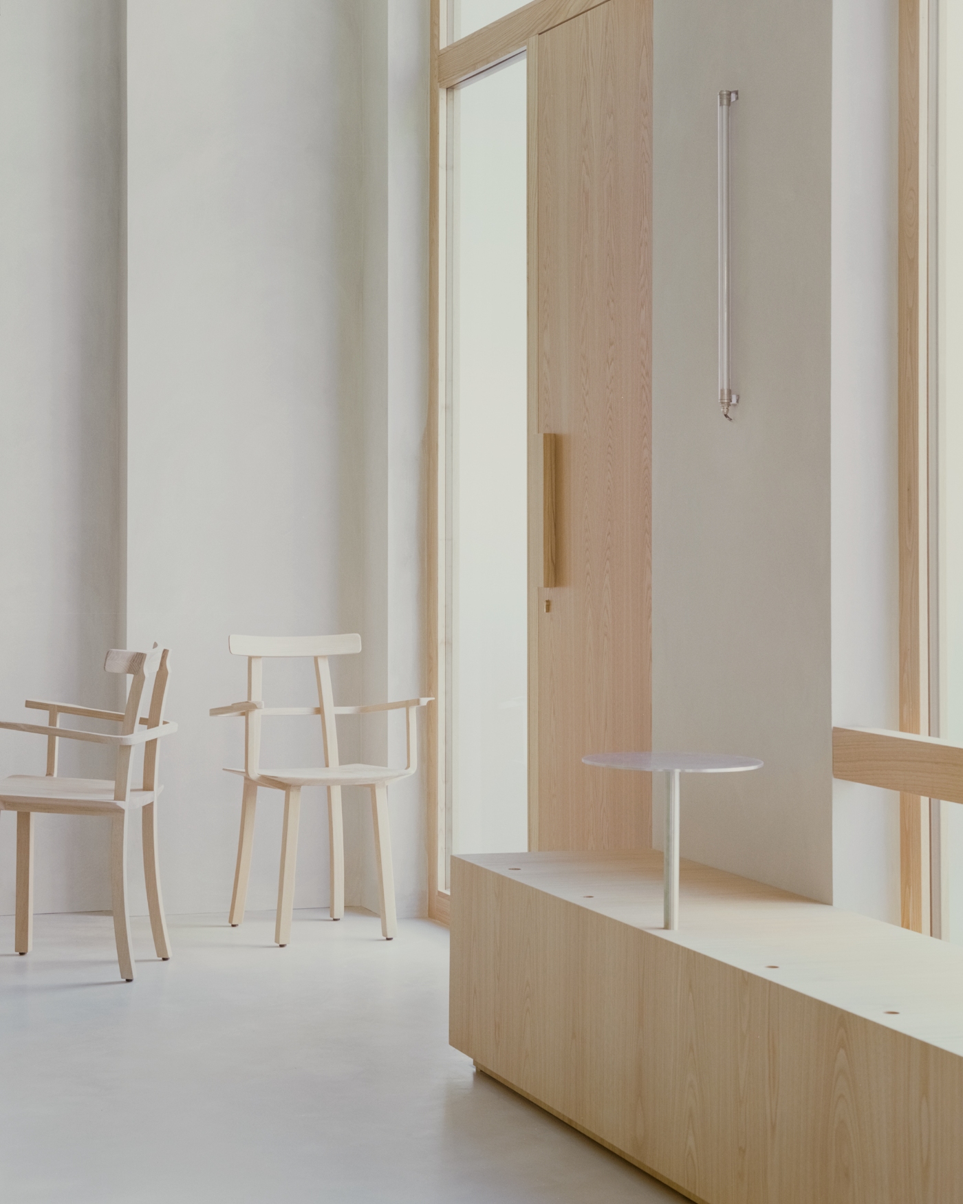 PAN Milano by studio wok — A threshold space at PAN Milano defined by chestnut wood framing and light wood furniture.