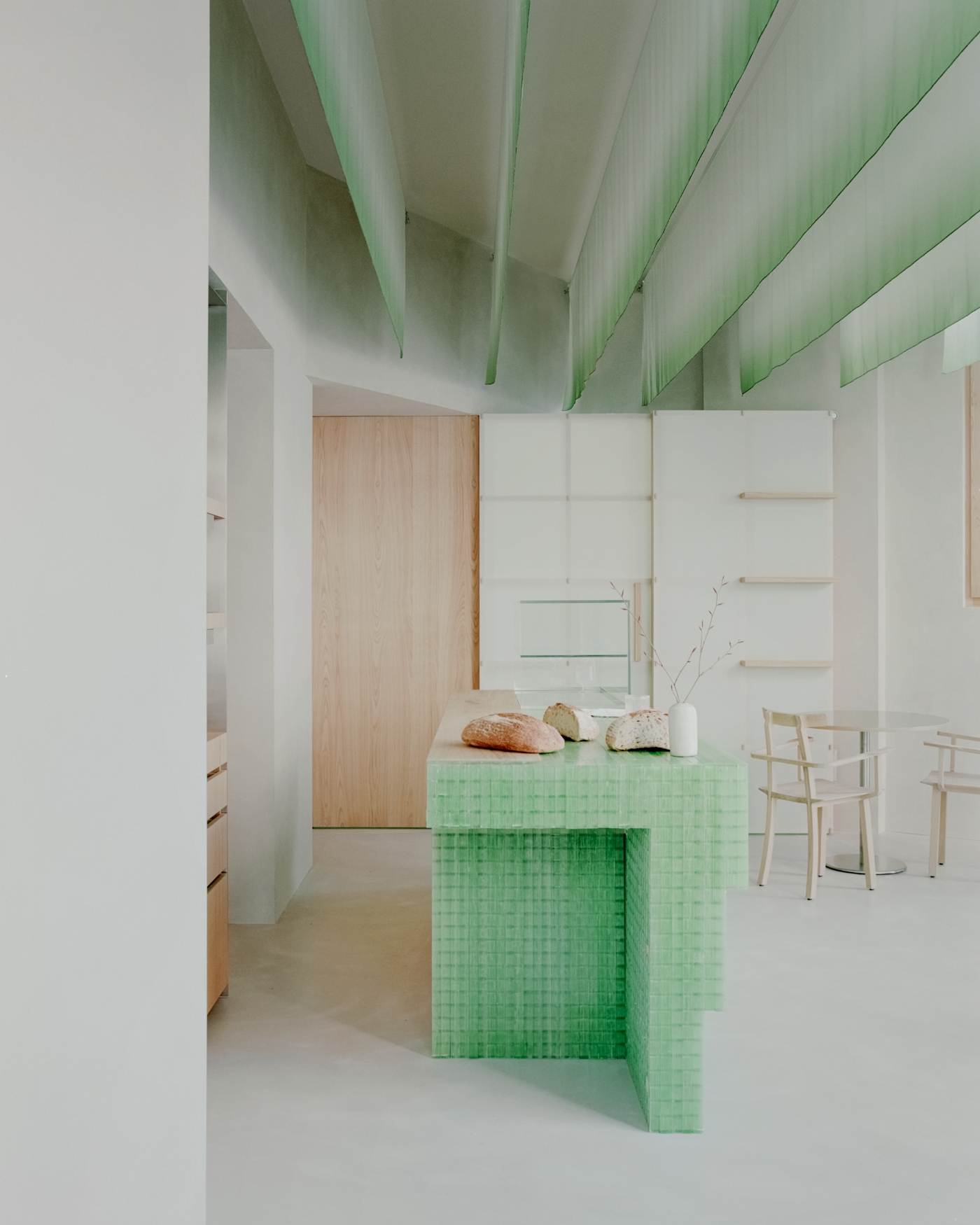 PAN Milano by studio wok — PAN Milano's counter anchors the open-plan space as a sculptural element, constructed from green fiberglass grating that glows softly under overhead light.