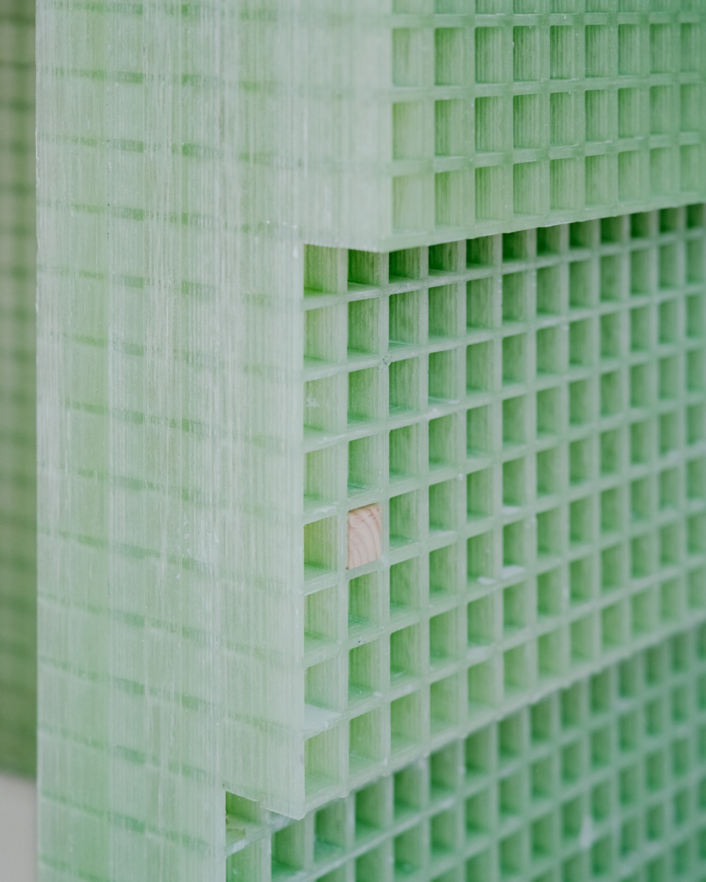 PAN Milano by studio wok — Close-up detail of PAN Milano's service counter, revealing the suspended green fiberglass grating surface with soft diffused luminosity.