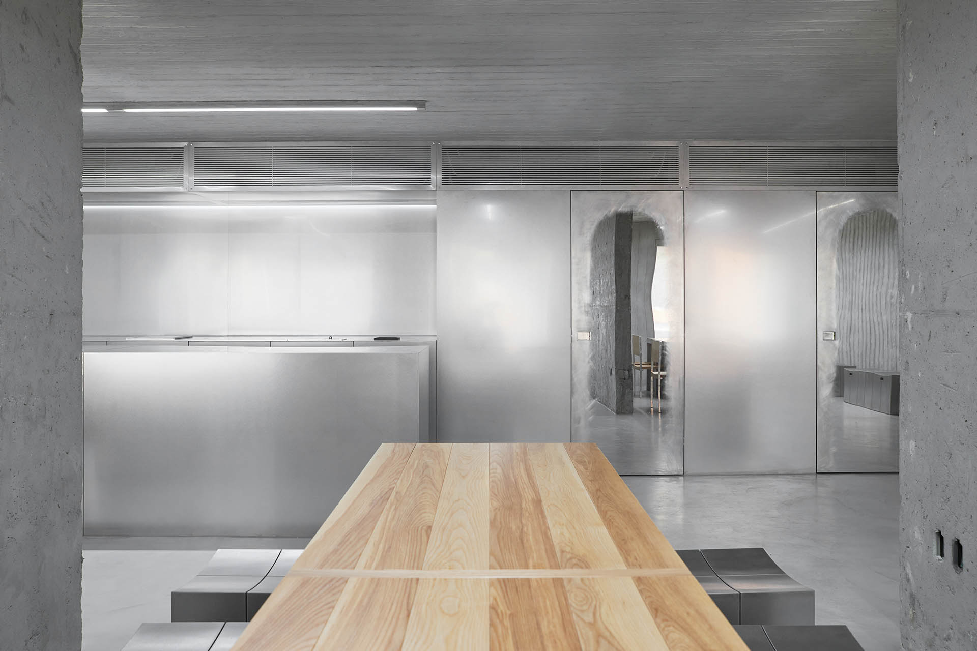 HAHOUSE Cafe by Niceworkshop — A timber table dominates the foreground, its light wood grain running horizontally across the frame.