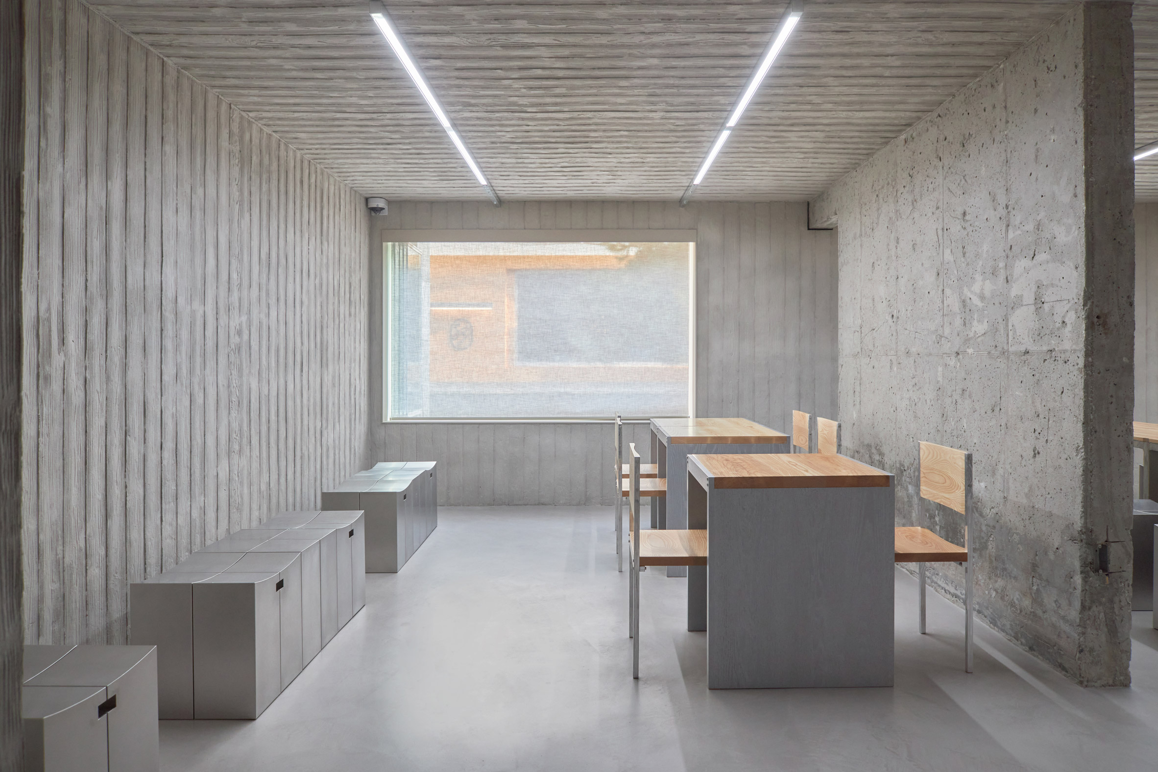 HAHOUSE Cafe by Niceworkshop — The cafe interior presents a studied material composition across three surfaces: walls clad in stainless steel etched with vertical wood-grain texture, a...