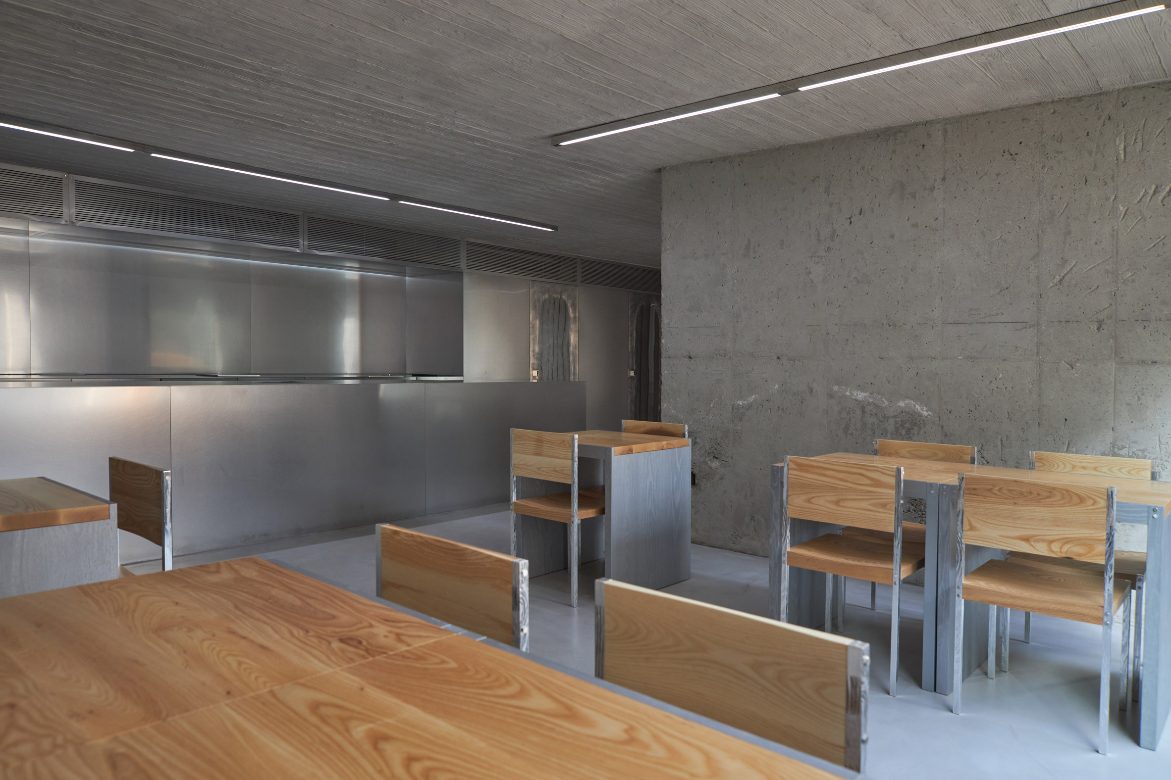 HAHOUSE Cafe by Niceworkshop — The cafe interior demonstrates material layering through dining furniture positioned in the foreground and middle ground.