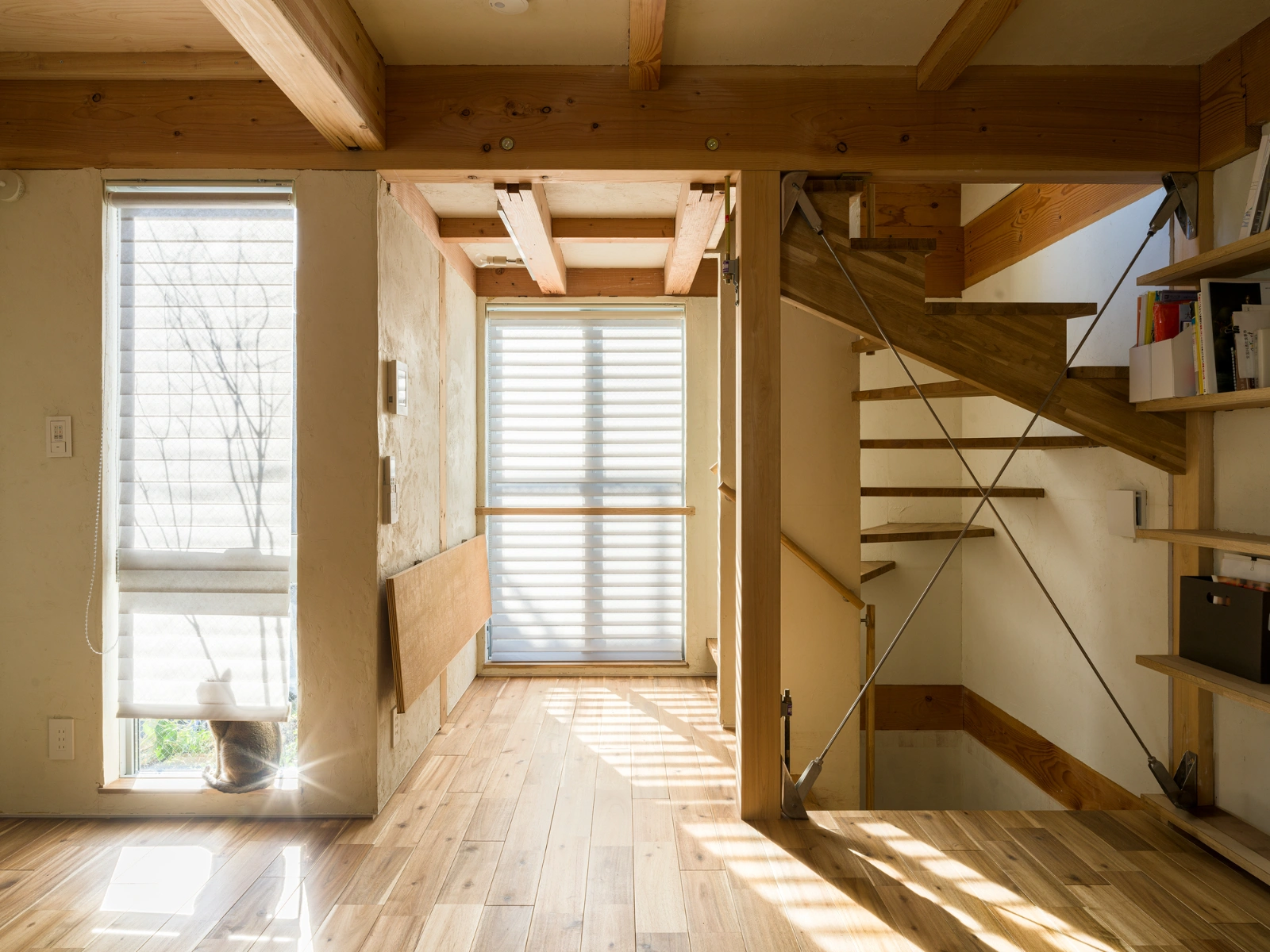 Small House on a Corner Lot by KOMINORU Design — Interior passage of the three-story timber-frame structure, captured from ground level looking toward the glazed rear facade.