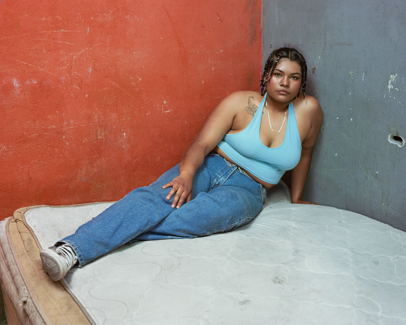 Bravo by Felipe Romero Beltrán — A portrait photograph taken at the junction of a two-tone rendered wall—terracotta-red and slate-grey divided vertically.