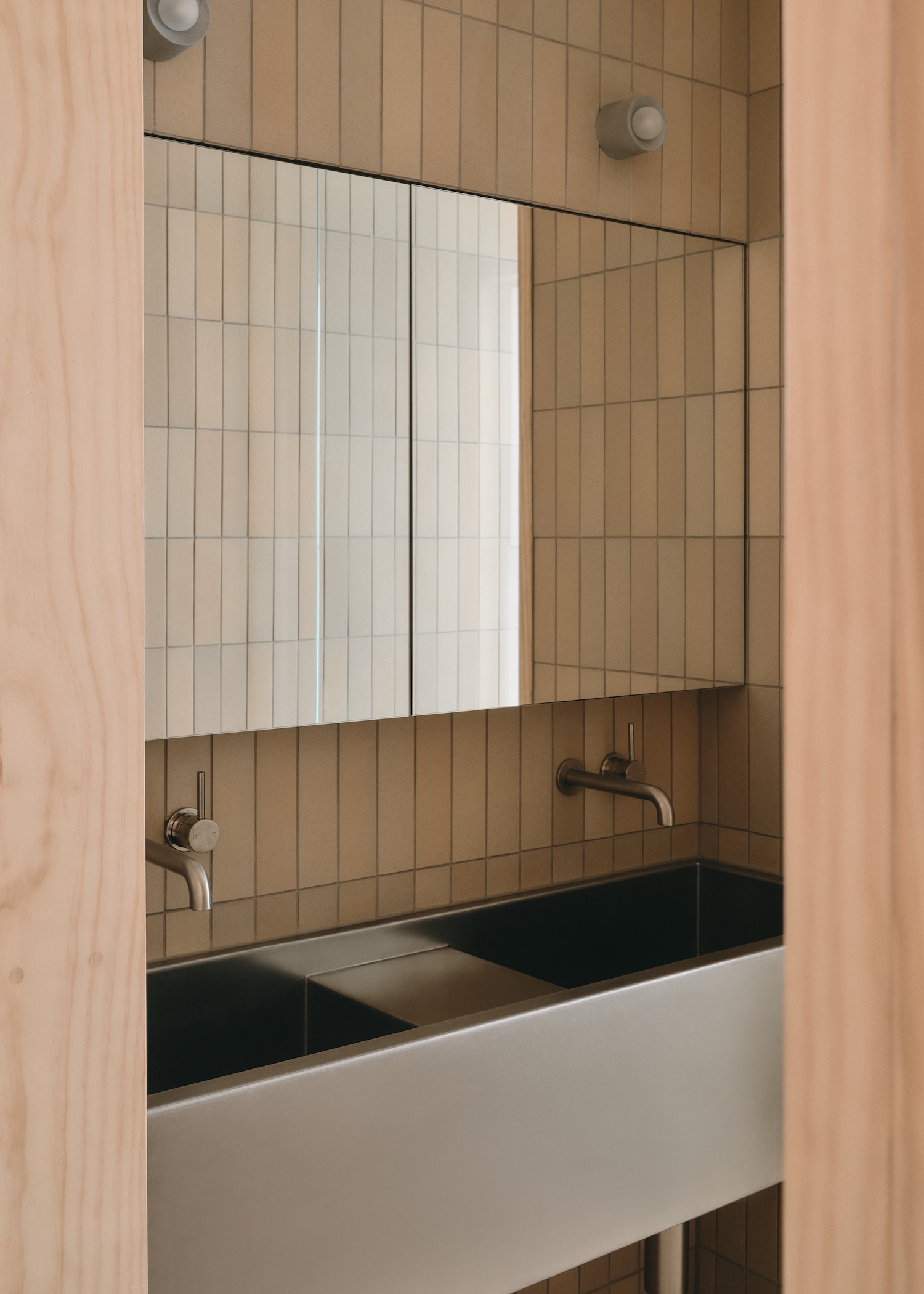 Mapleton House by Atelier Chen Hung — The ensuite bathroom demonstrates restrained material composition through vertical timber-board cladding in warm ochre tones, interrupted by a horizontal...