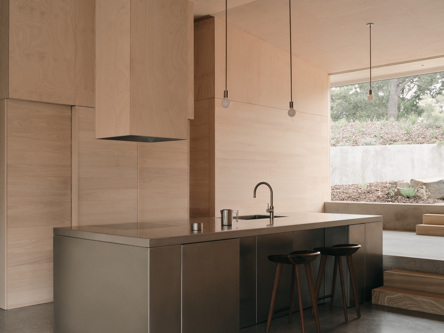 Mapleton House by Atelier Chen Hung — The kitchen island anchors the open-plan volume as a sculptural counterpoint to the rendered walls.