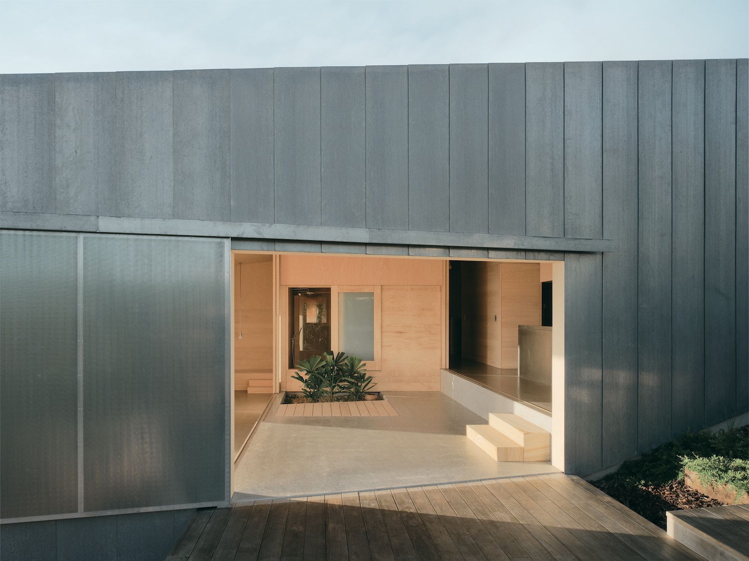 Mapleton House by Atelier Chen Hung — The threshold moment of Mapleton House unfolds across a concrete platform, where the transition from exterior timber deck to interior rendered cavity...