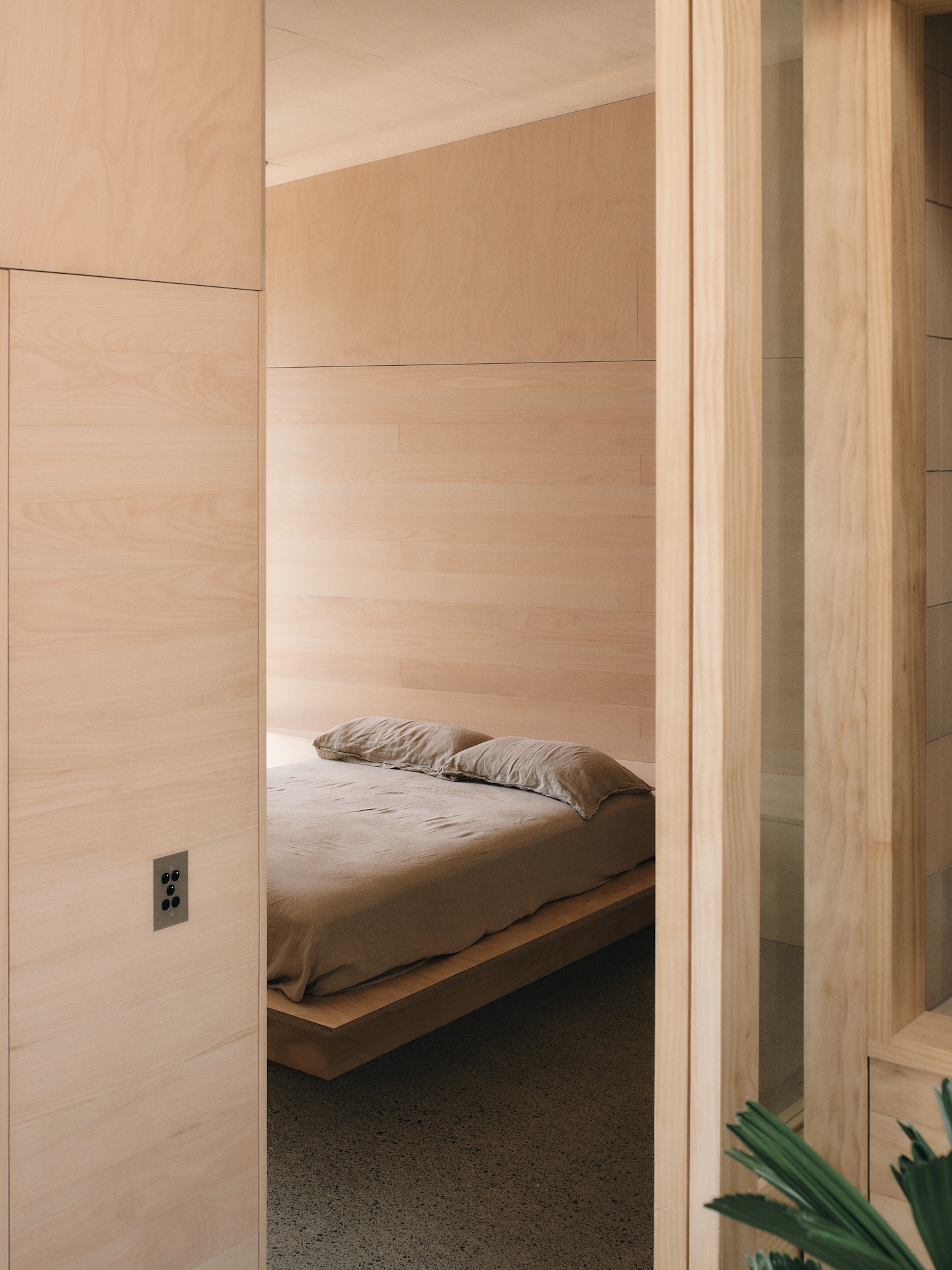 Mapleton House by Atelier Chen Hung — A built-in sleeping alcove recessed into rendered walls in warm ochre tones, accessible through a timber-framed opening.