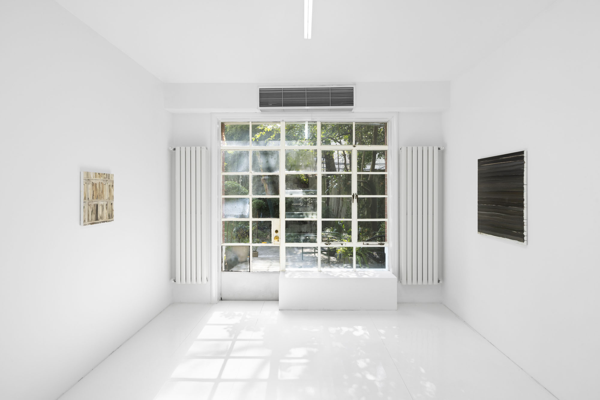 Four Minutes After Sunset by Rudy Cremonini at Capsule Shanghai — A gallery interior rendered in white plaster and polished concrete floors, bisected by a continuous linear light fixture suspended vertically through the...