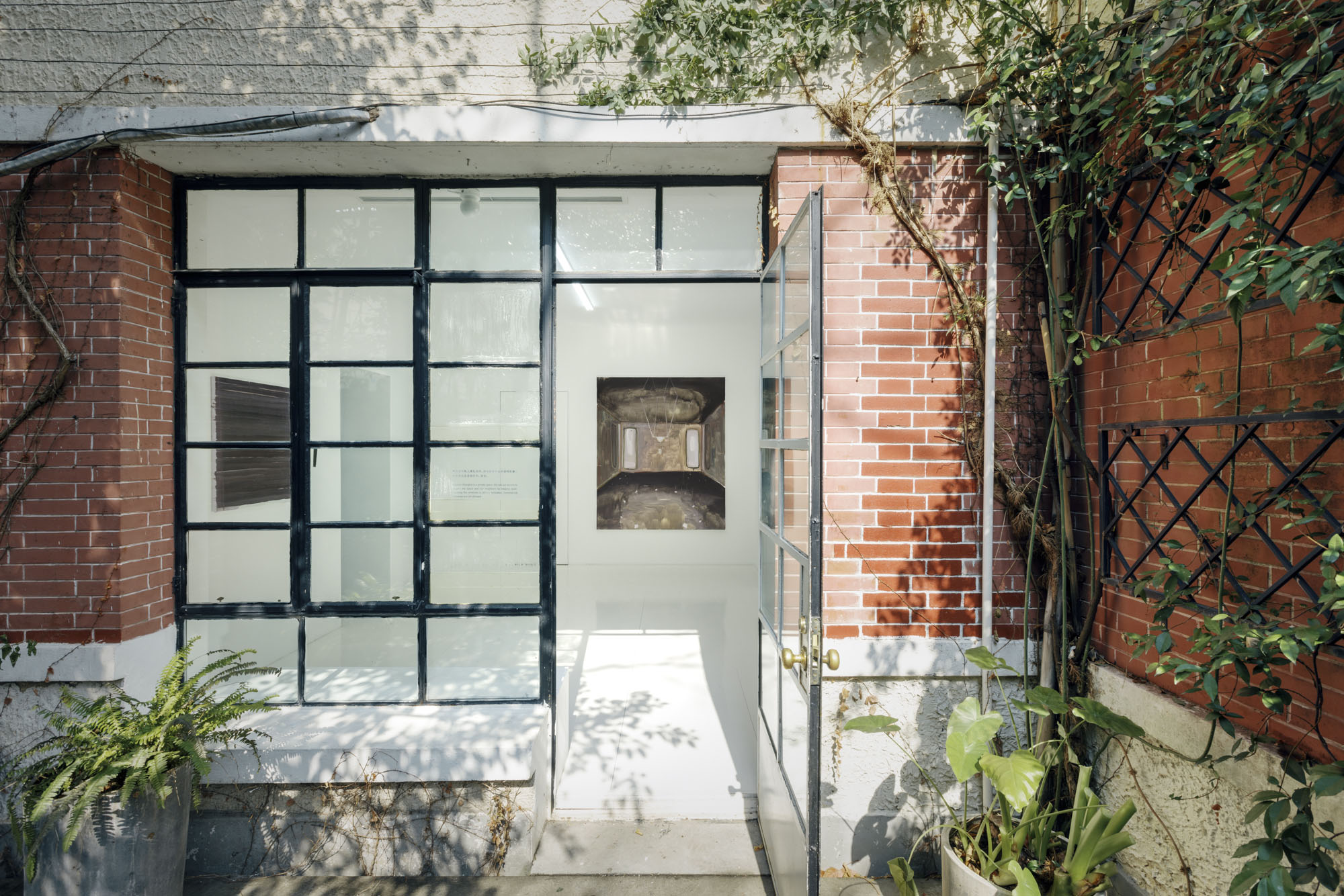 Four Minutes After Sunset by Rudy Cremonini at Capsule Shanghai — A gallery threshold frames the exhibition entrance, defined by a black-gridded storefront window of fifteen panes aligned with the brick perimeter wall.
