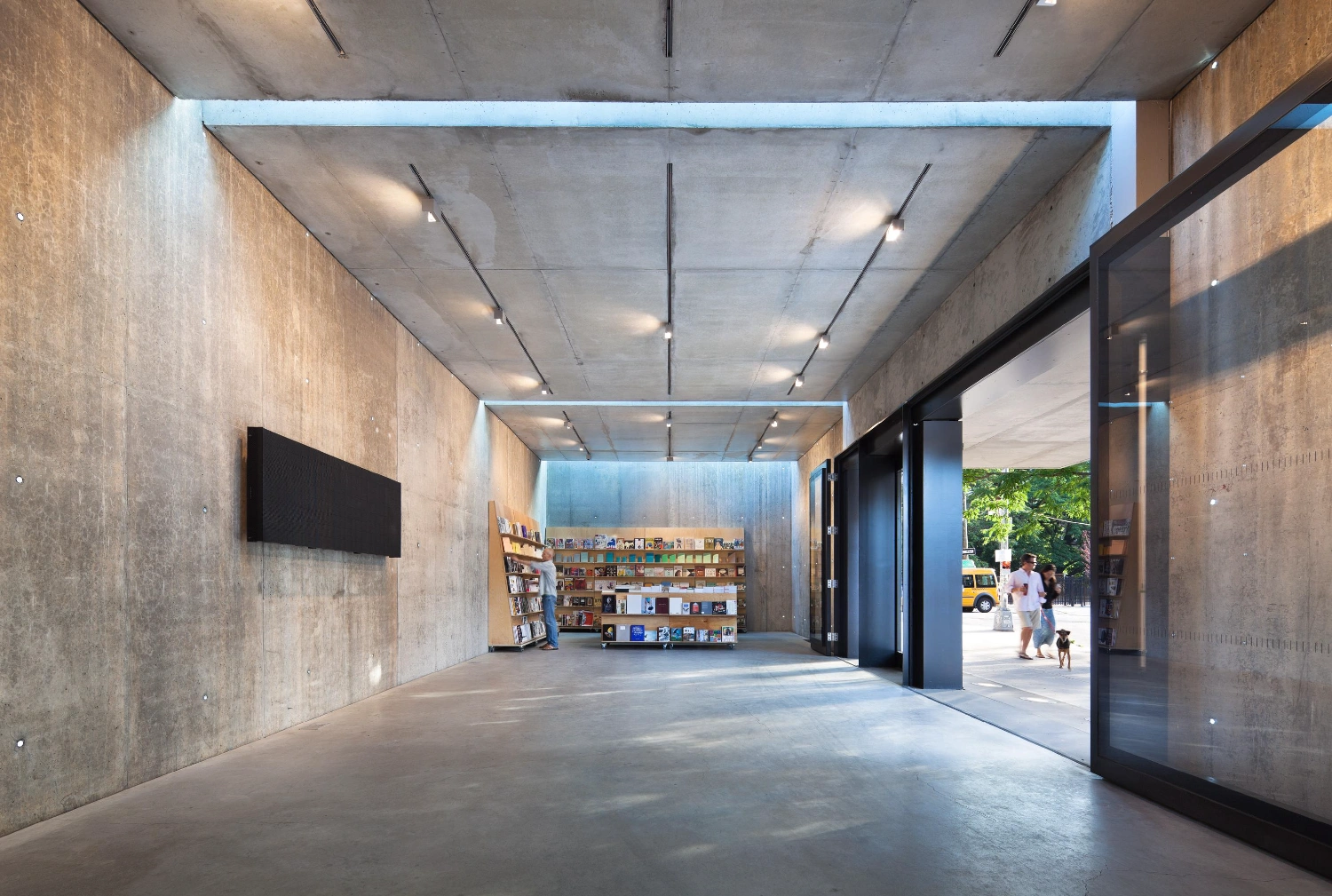 MoMA PS1 Entrance Building by Andrew Berman Architect — The entrance threshold of MoMA PS1's gateway building presents a monolithic concrete interior defined by board-formed cast walls and a continuous linear...