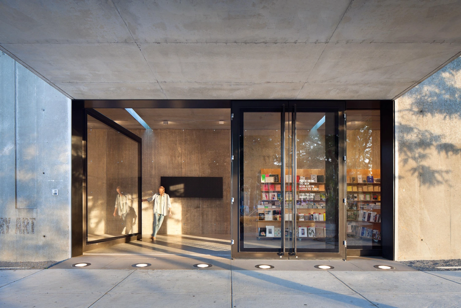MoMA PS1 Entrance Building by Andrew Berman Architect — The entrance pavilion presents a monolithic concrete facade punctuated by recessed glazing that frames the interior threshold.