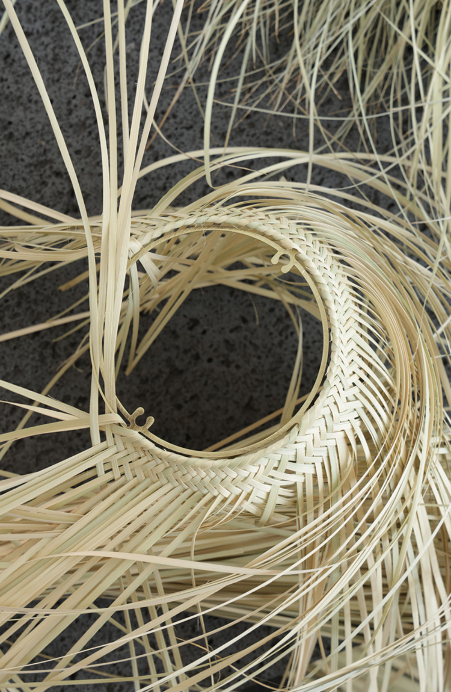 Cilia by Studio Davidpompa — Close-up detail of the Cilia lamp's hand-woven palma shade, revealing the intricate weaving structure and concentric circular patterns that form the...