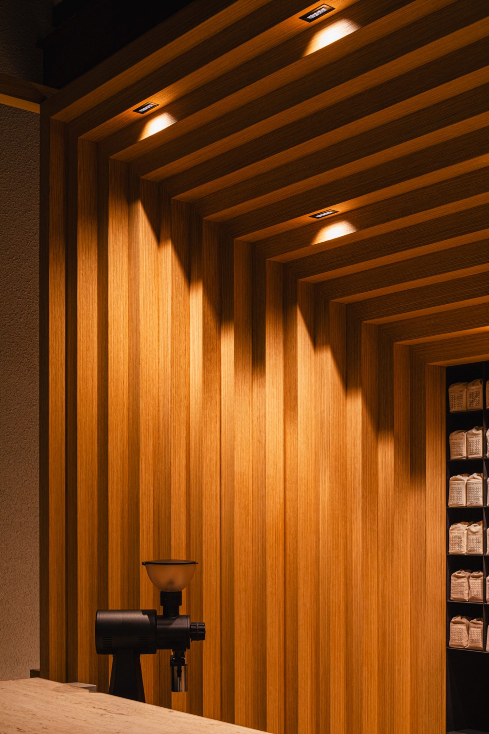Koffee Mameya Kakeru by Fourteen Stones Design — Night photograph of the Koffee Mameya Kakeru interior, captured through the frameless glass storefront.