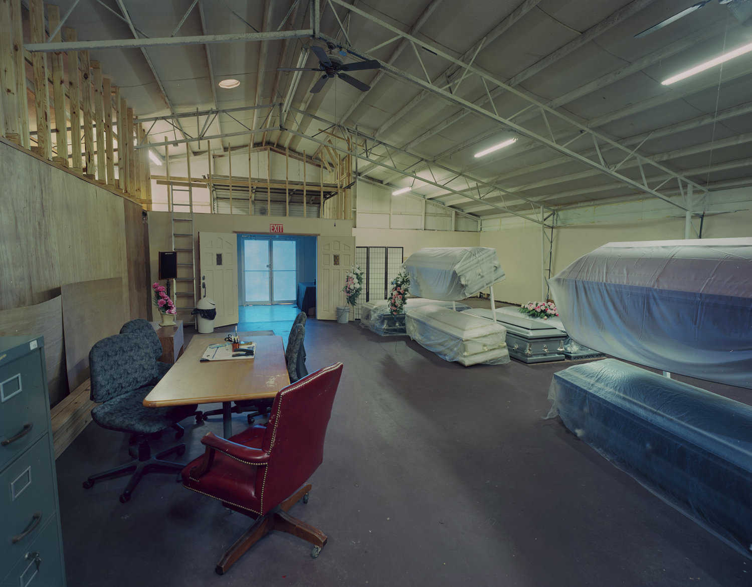 Funeral Homes of the American South by Timothy Hursley — A showroom interior displaying caskets arranged across an industrial warehouse space.