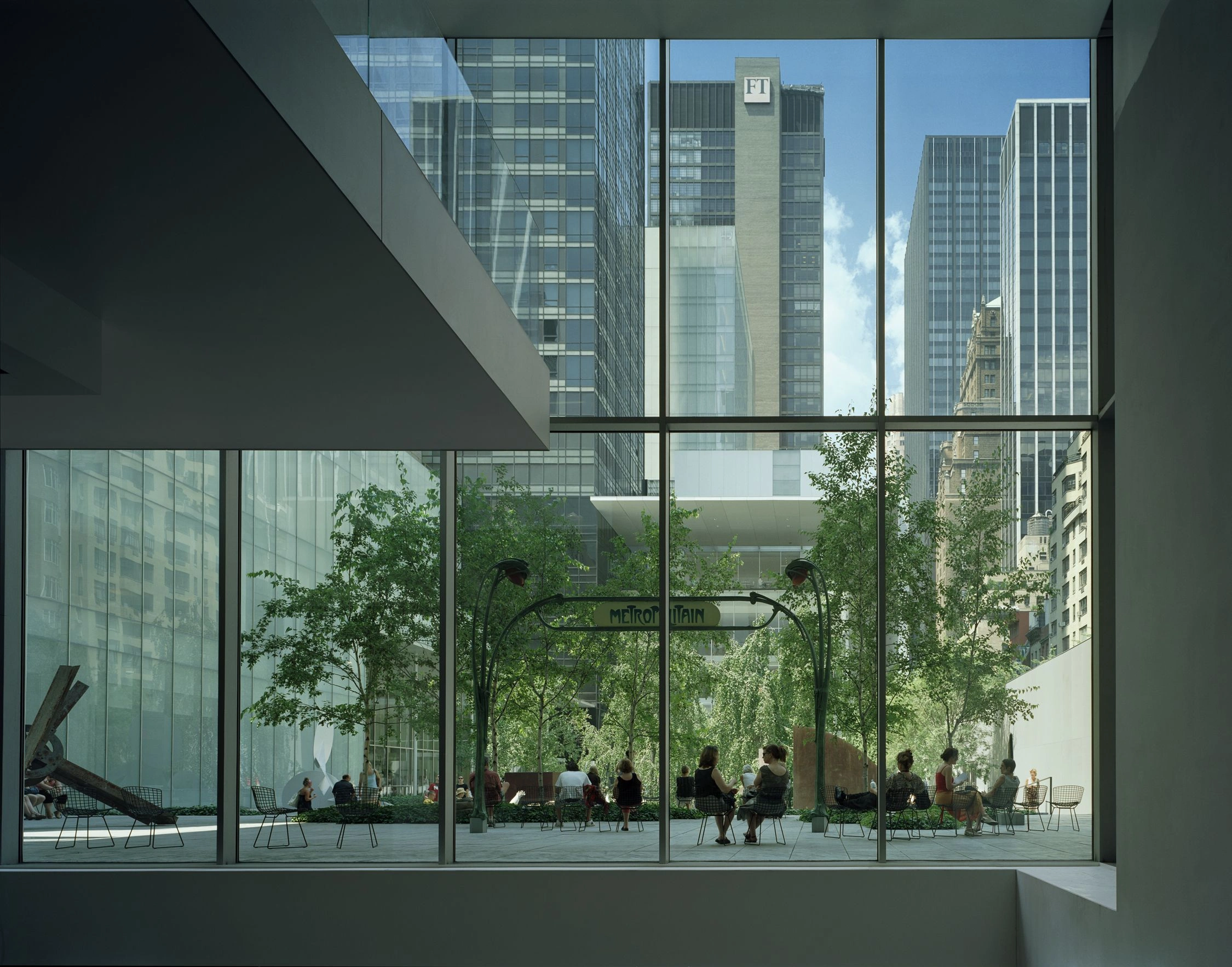 Museum of Modern Art in New York by Yoshio Taniguchi — Ground-level perspective through expansive frameless glass curtain wall reveals MoMA's street-facing courtyard.