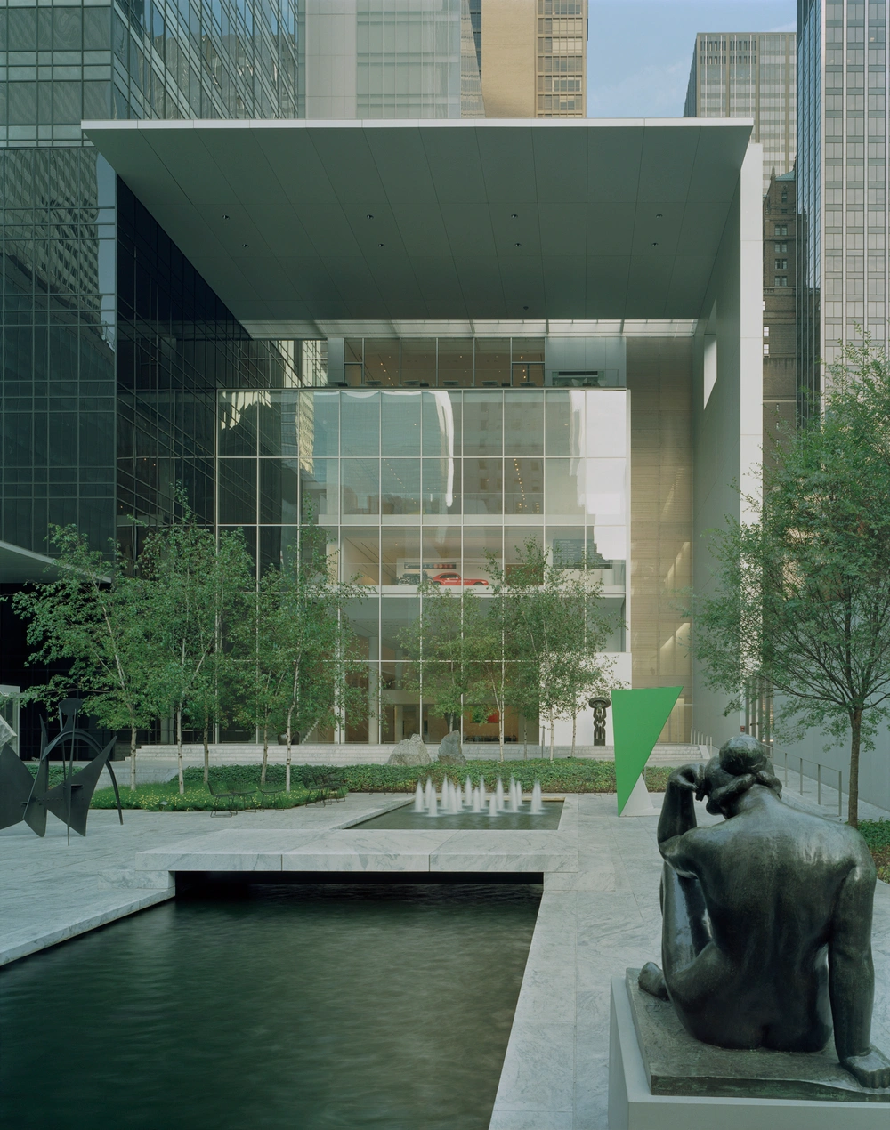 Museum of Modern Art in New York by Yoshio Taniguchi — A courtyard view of Taniguchi's MoMA addition frames the expansive glass curtain wall at street level, where minimal framing allows unobstructed sightlines...