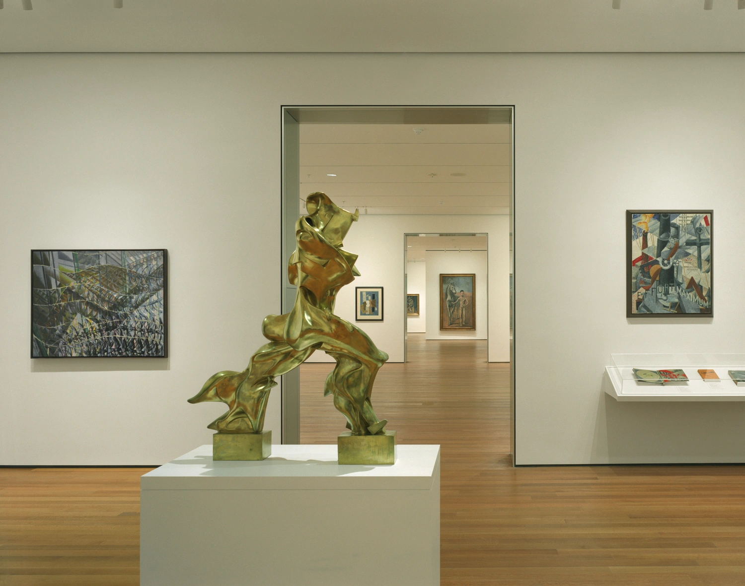 Museum of Modern Art in New York by Yoshio Taniguchi — A brass sculptural figure in dynamic pose occupies the foreground on a white plinth, its patinated surface catching gallery lighting.