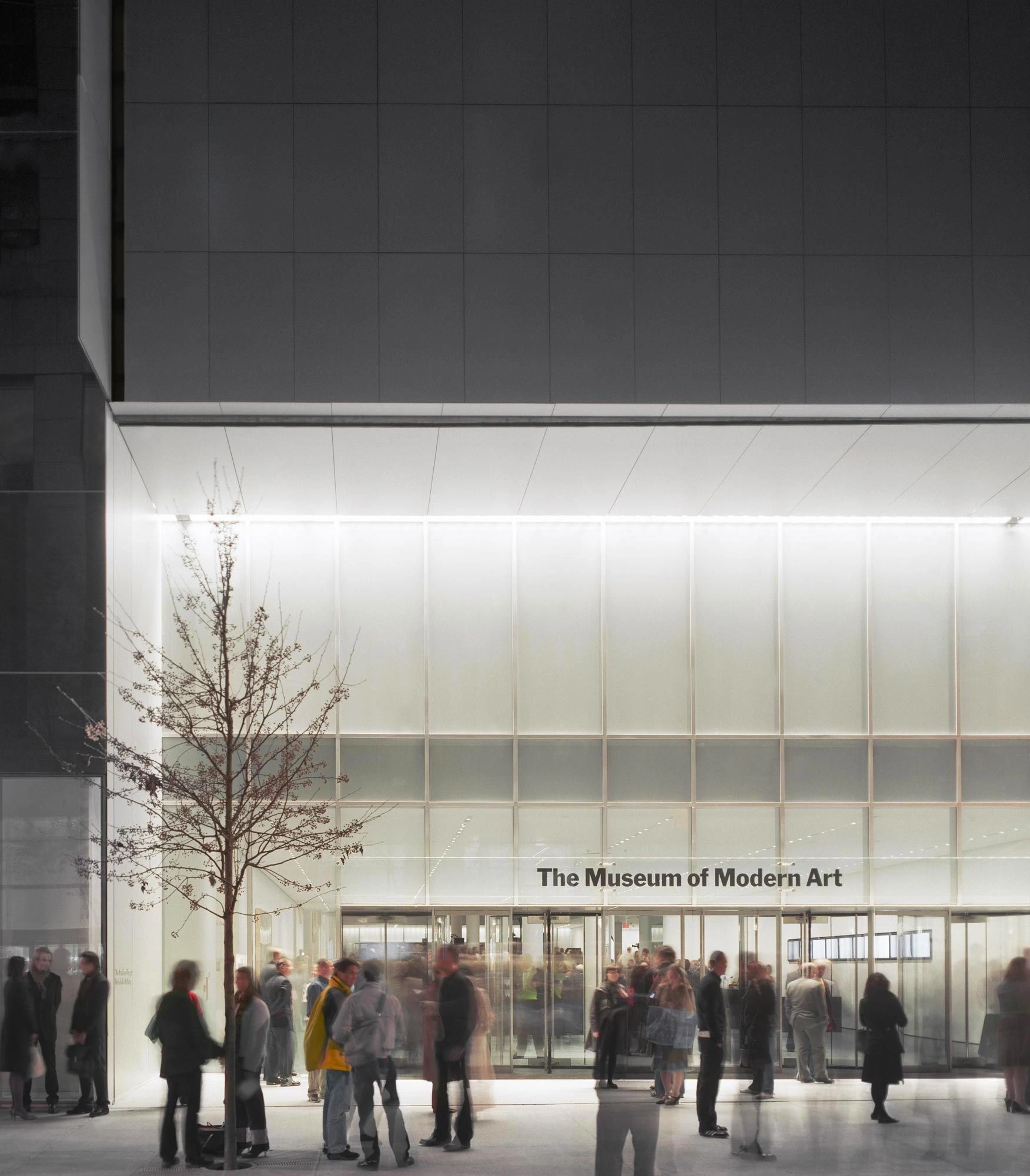 Museum of Modern Art in New York by Yoshio Taniguchi — The street-level entrance of MoMA's 2004 expansion presents a transparent threshold defined by a continuous glass curtain wall with minimal aluminum framing.